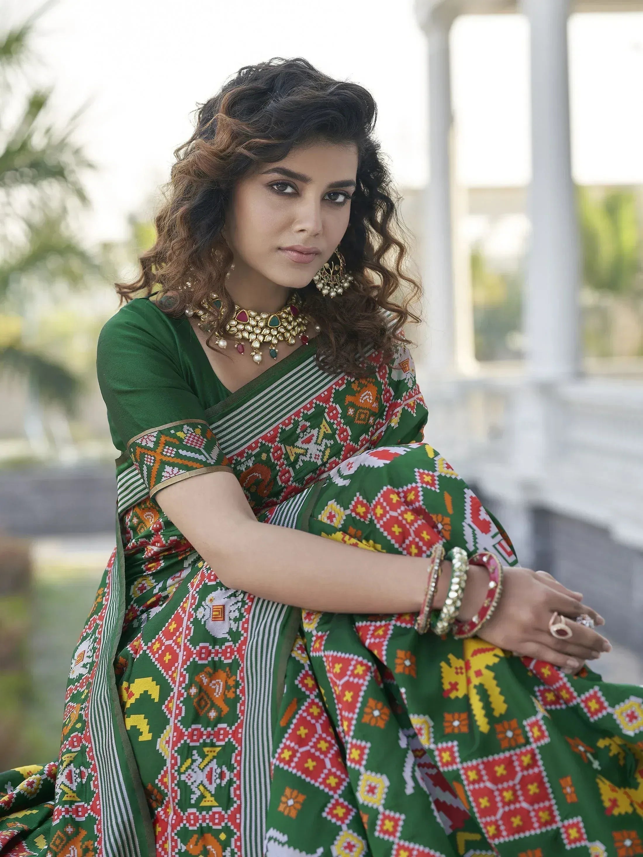 Woman in vibrant green printed saree with ethnic jewelry, perfect for festive occasions