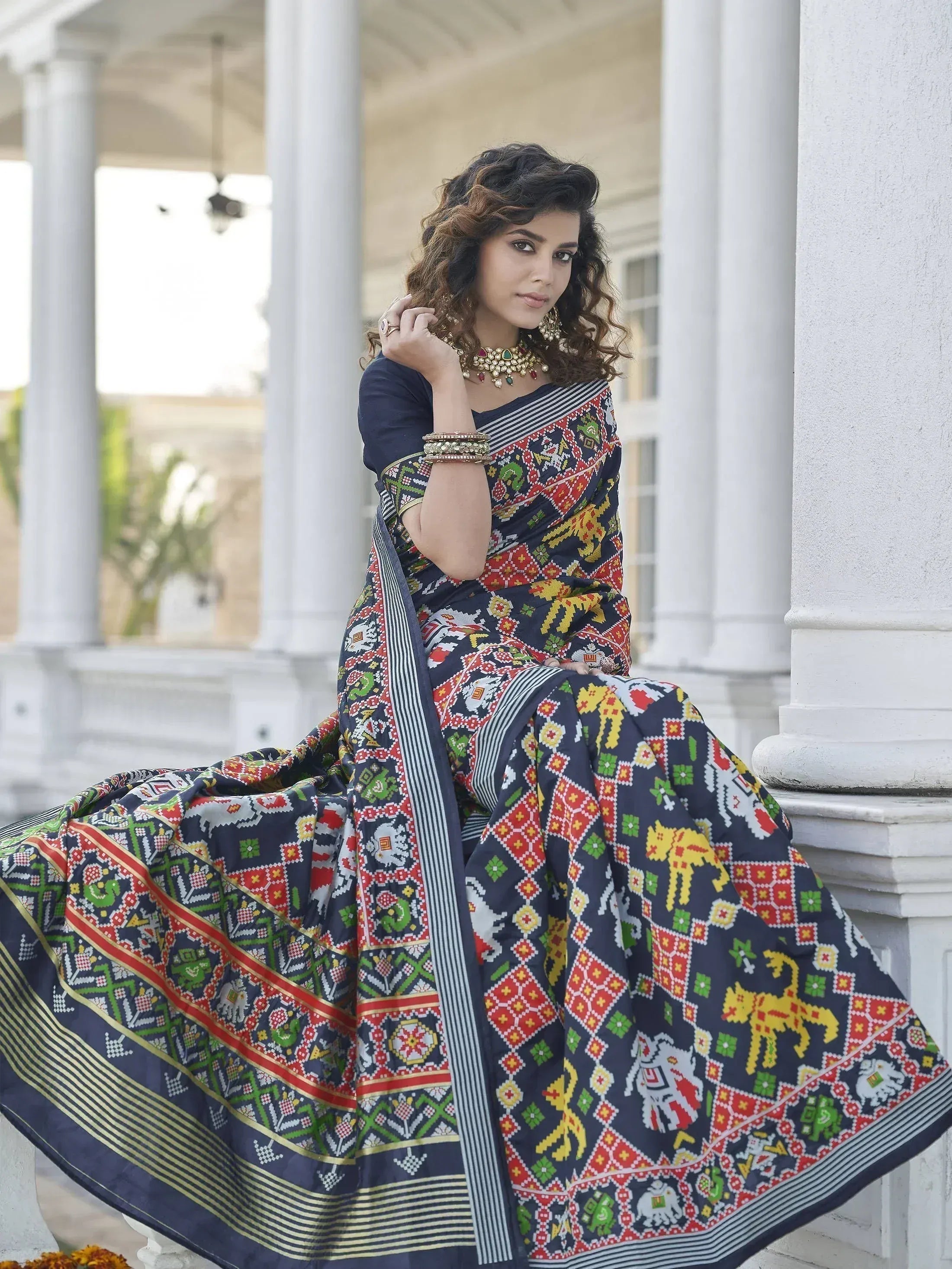 Woman in vibrant printed ethnic saree with elephant motifs, styled with traditional jewelry for festive occasions.