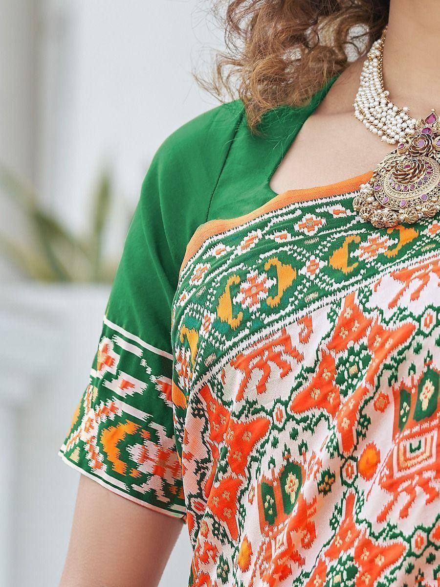 Green and orange printed ethnic saree with matching blouse and traditional jewelry