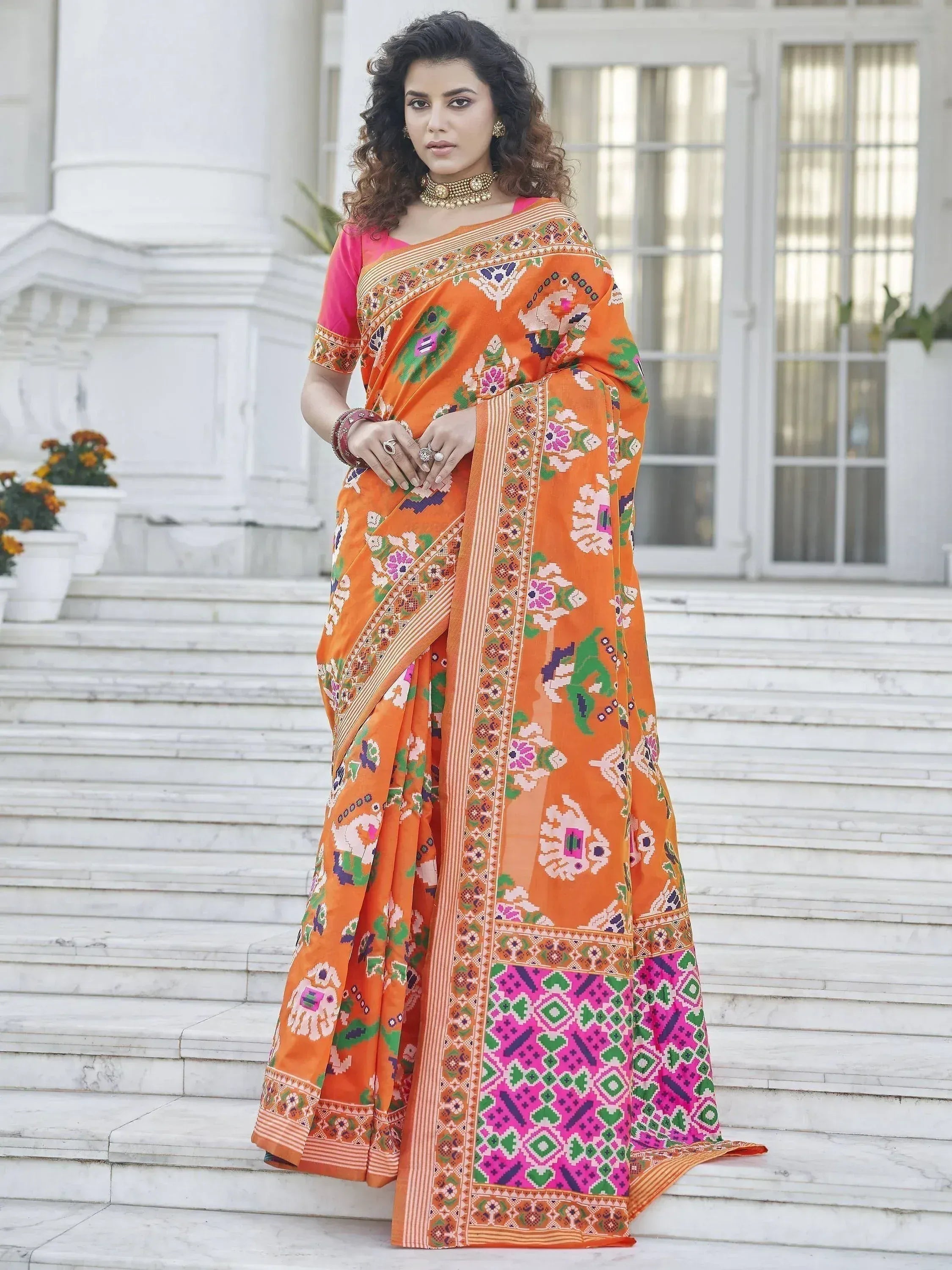 Vibrant orange saree with floral and geometric patterns, paired with a pink blouse, perfect for ethnic occasions.