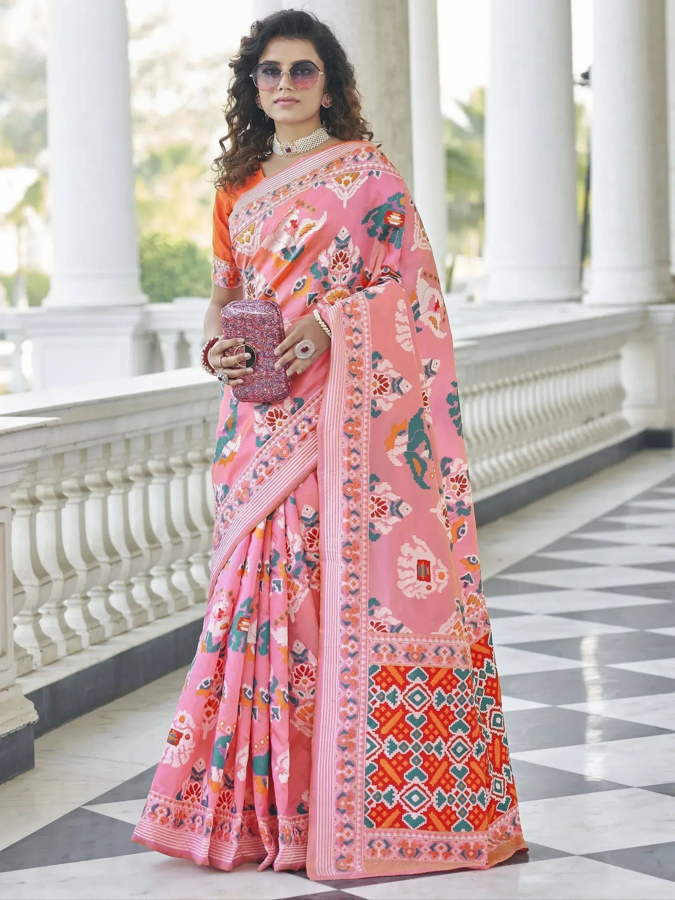 Pink printed saree with elephant motifs, orange blouse, and statement jewelry for ethnic wear