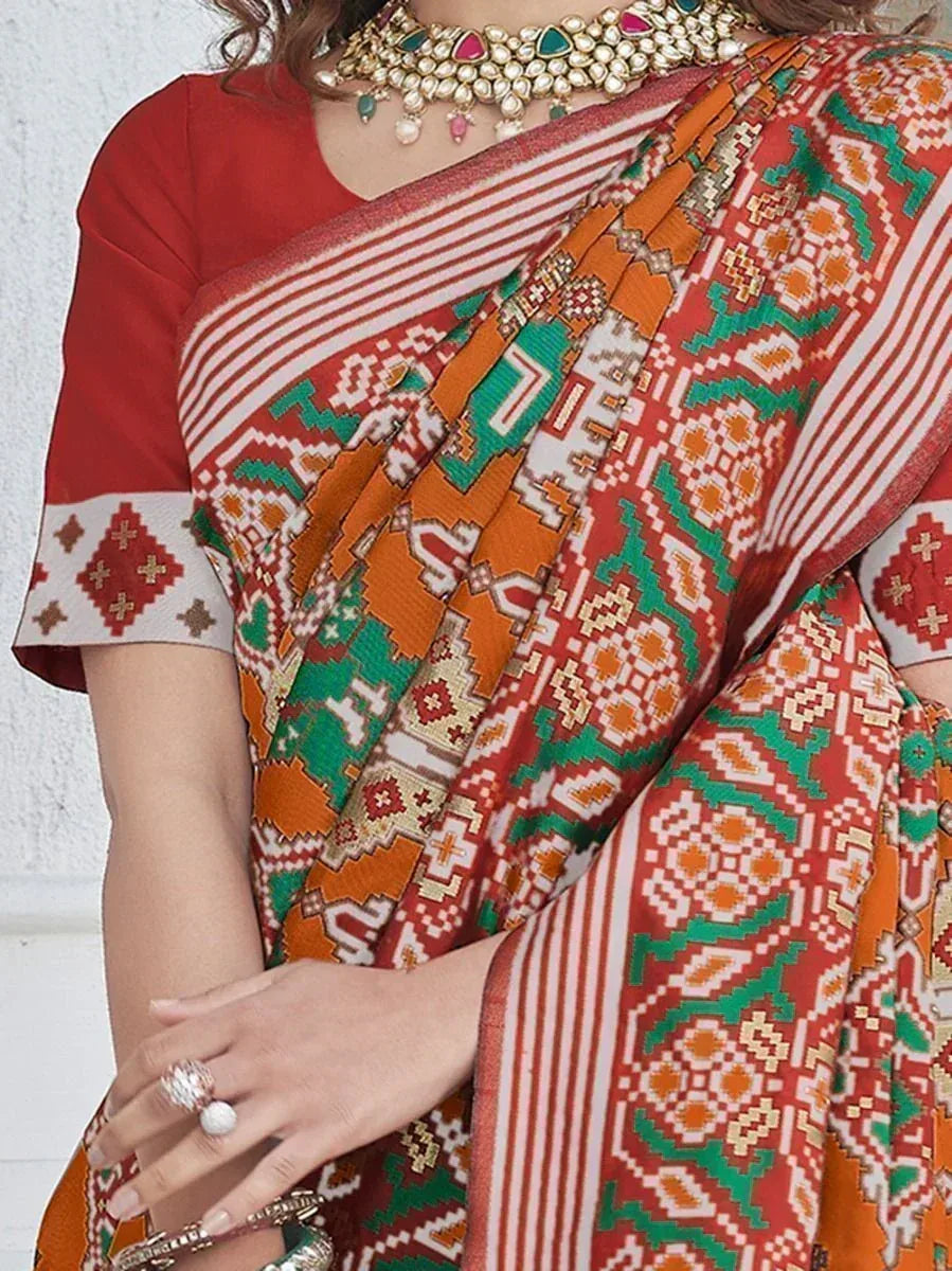 Vibrant red and green printed saree with geometric patterns, paired with traditional jewelry and blouse.