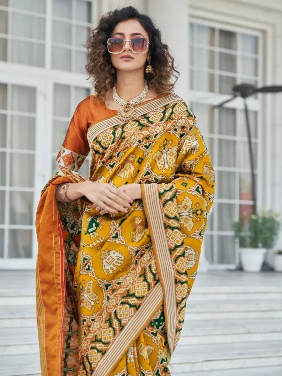 Yellow and green printed saree with elephant motifs, paired with orange blouse, styled for ethnic wear