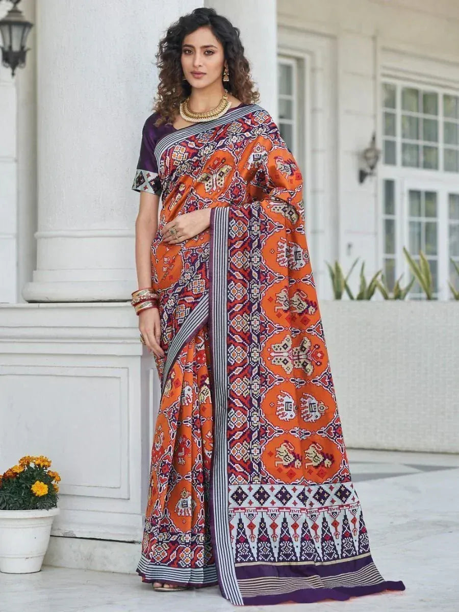 Orange and purple printed saree with geometric patterns, styled with gold jewelry for ethnic wear