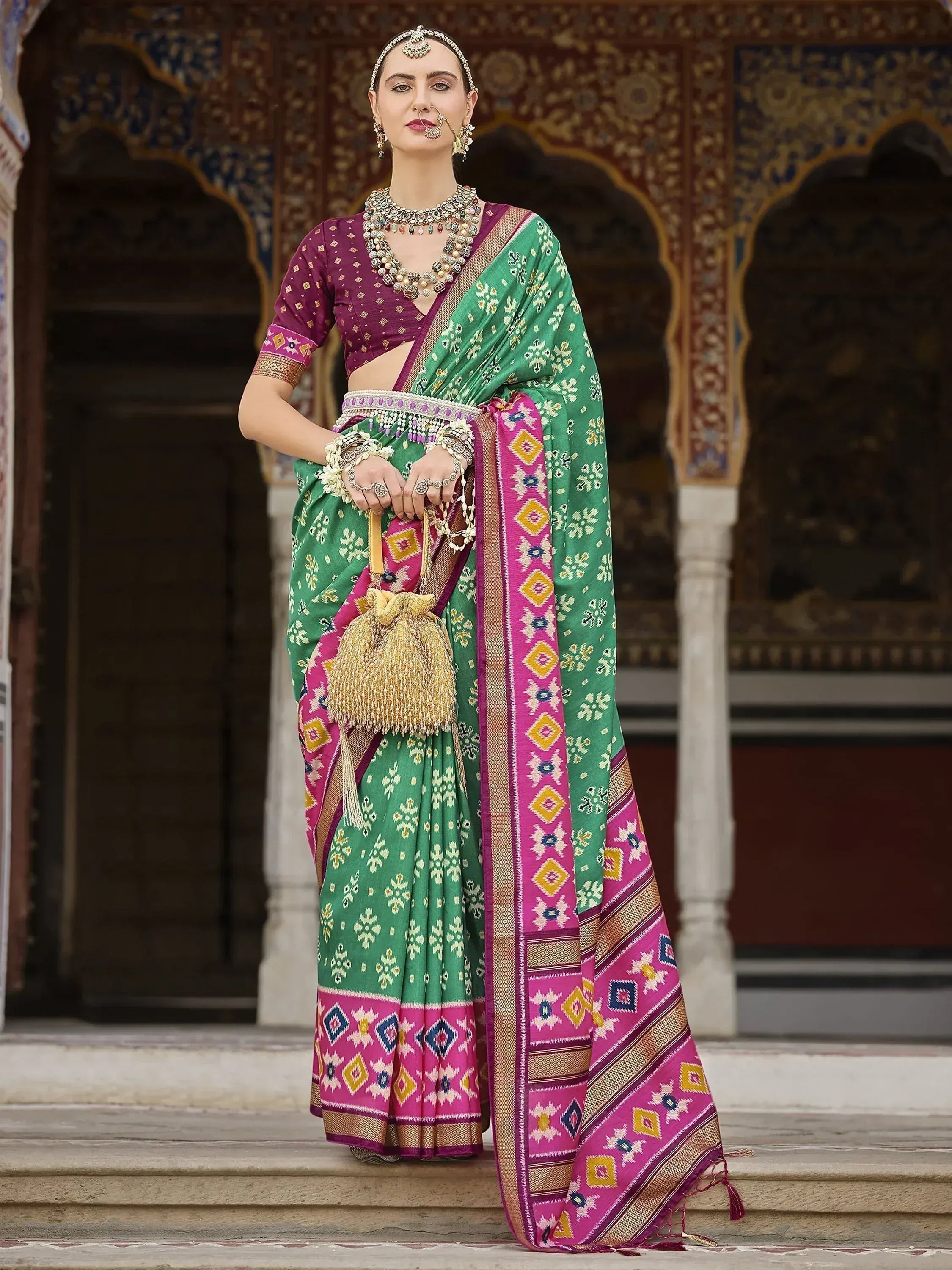 Green and pink printed saree with ethnic jewelry, perfect for Indian weddings and festive occasions.