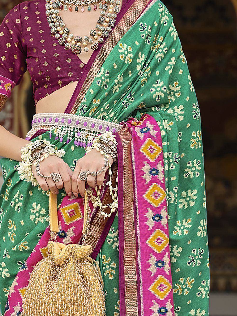 Green and pink ethnic saree with gold embroidery, paired with purple blouse and traditional jewelry