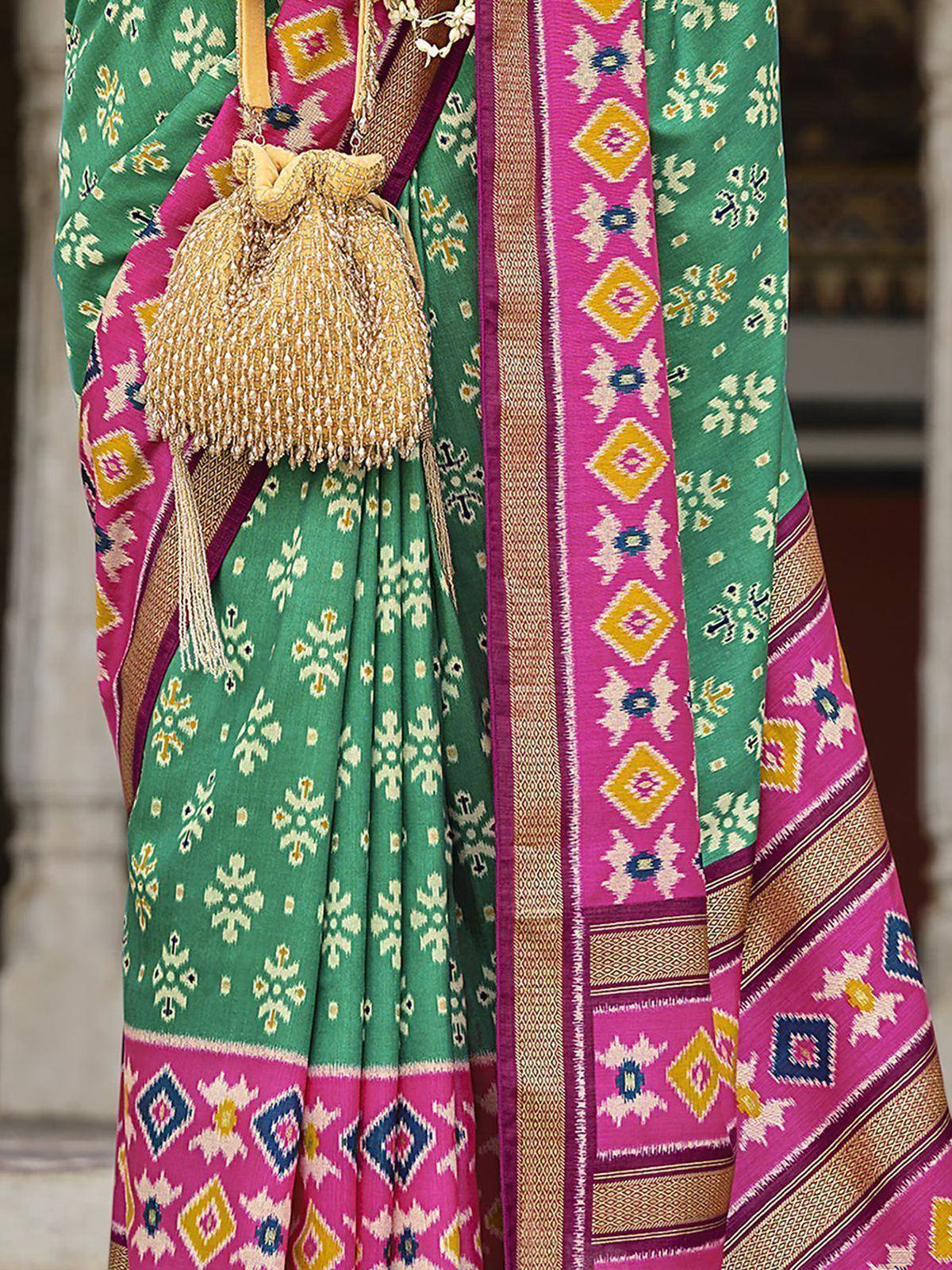Green and pink ikat saree with geometric patterns and gold tassels, perfect for ethnic occasions