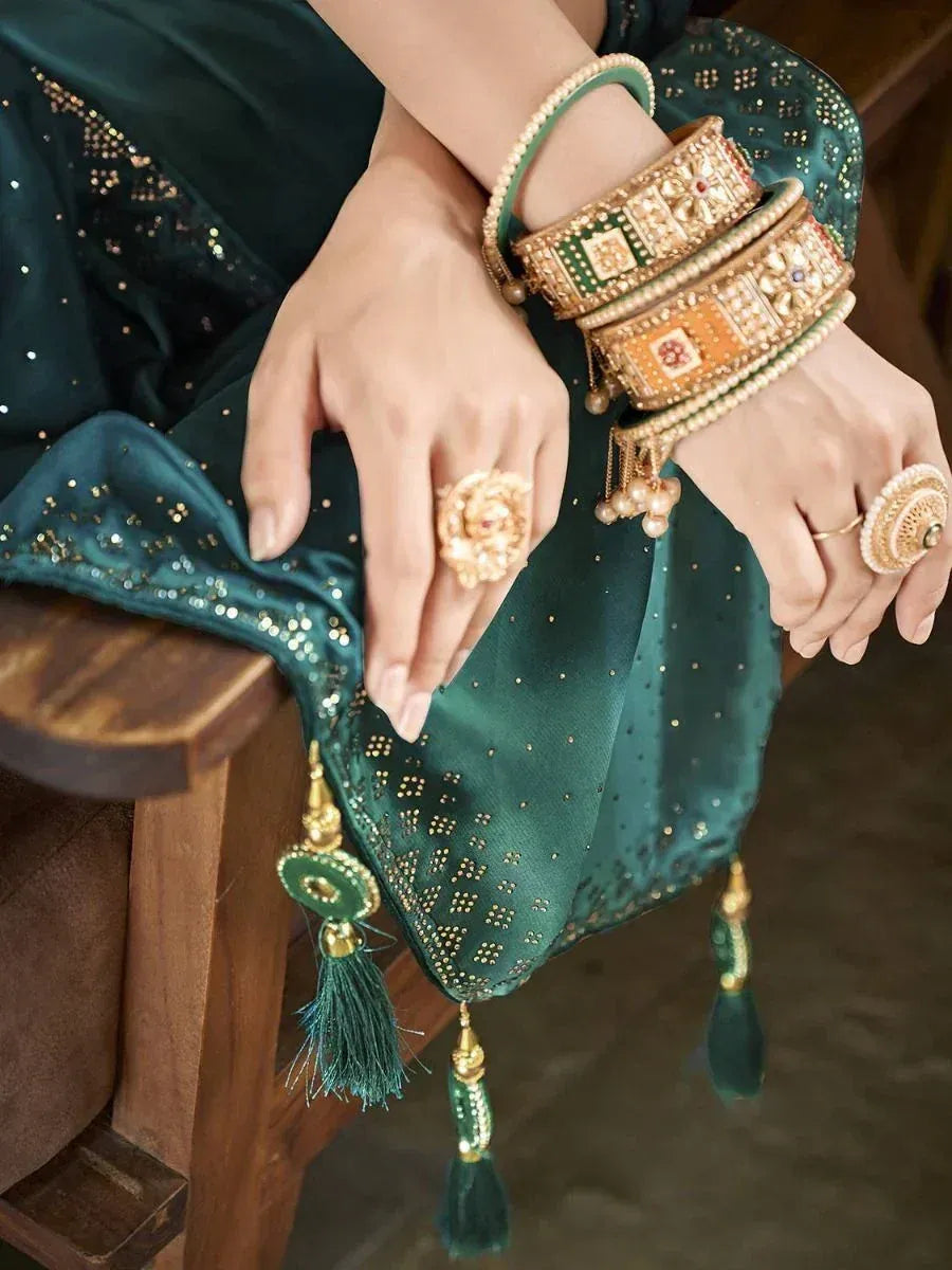 Emerald green ethnic saree with gold embroidery, paired with traditional bangles and statement rings