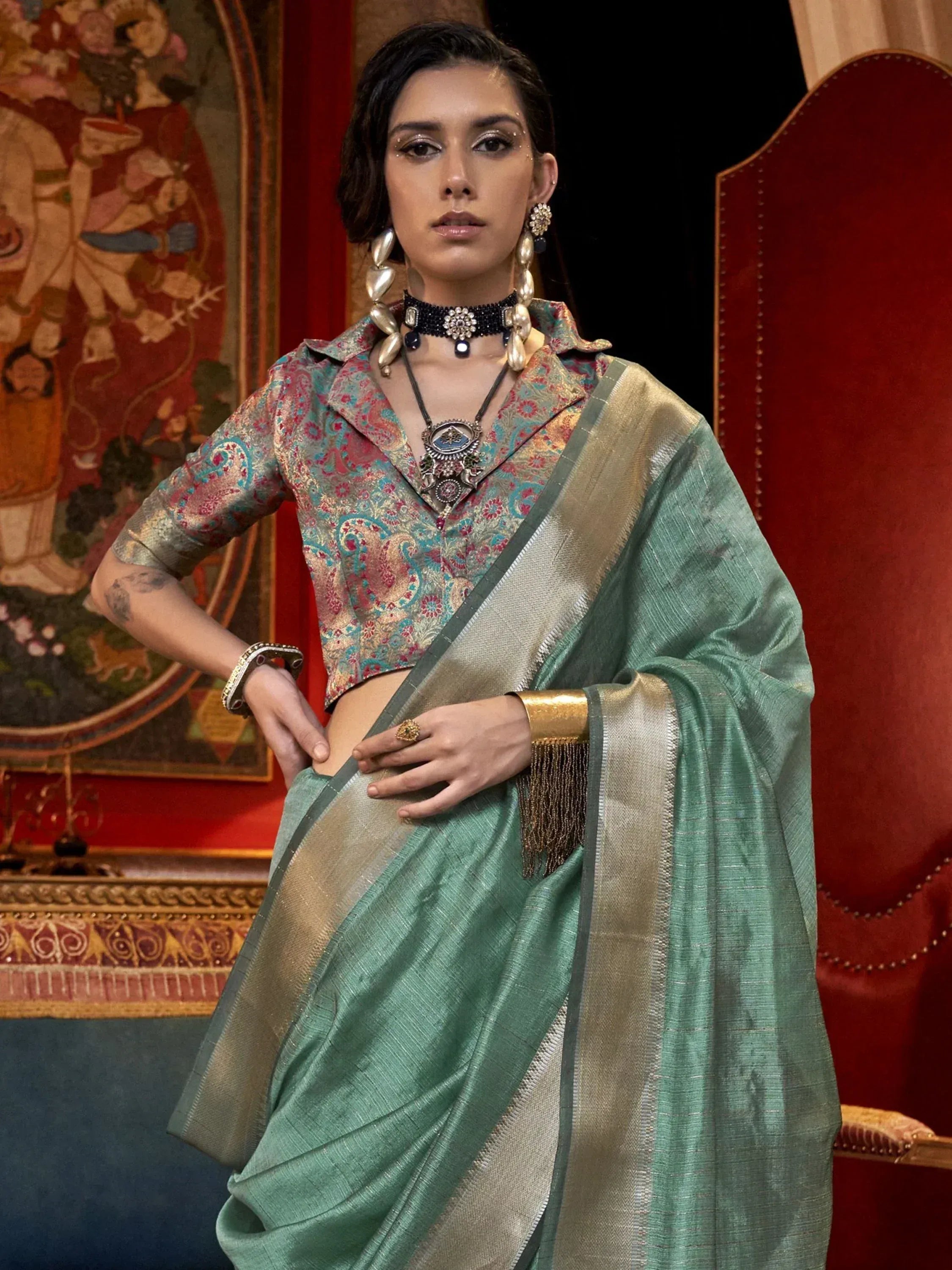Woman in mint green saree with gold border and printed blouse, styled with ethnic jewelry for Indian occasions