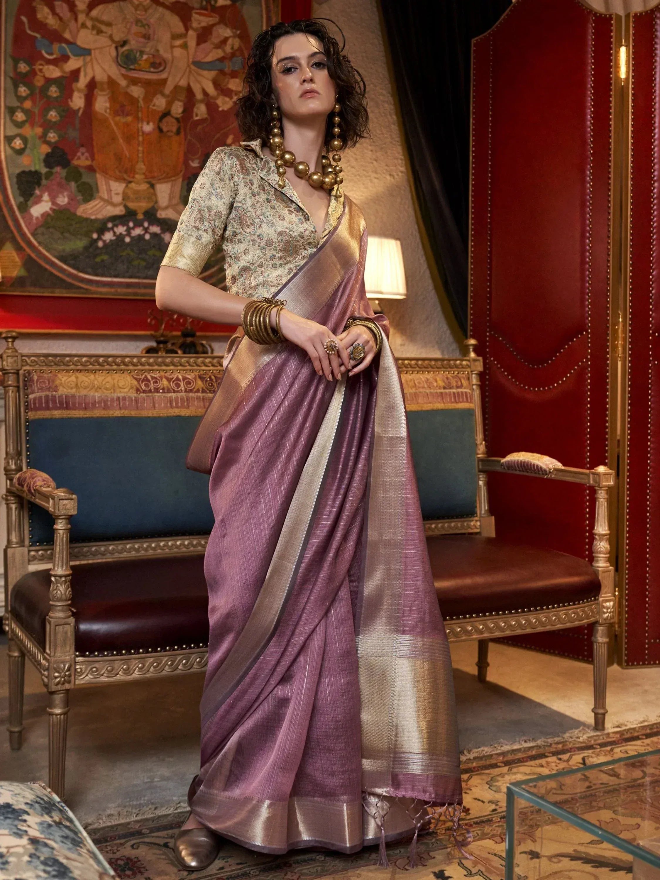 Elegant woman in purple silk saree with gold border, floral blouse, and traditional jewelry for Indian ethnic wear.
