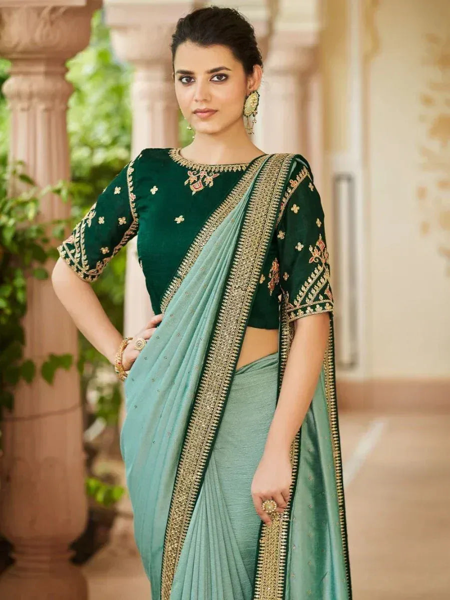 Emerald green embroidered blouse with light blue saree, gold border, perfect for Indian ethnic wear occasions