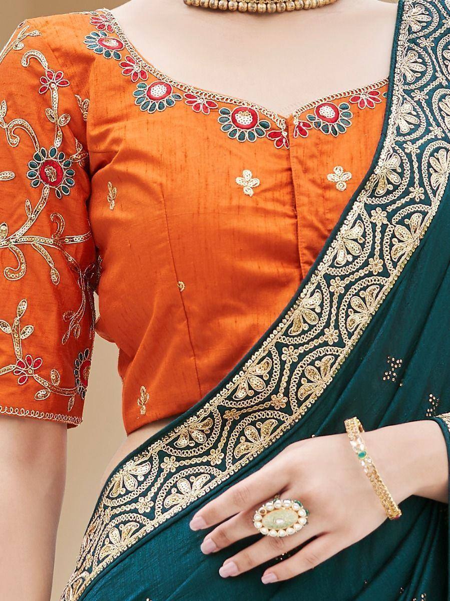 Orange embroidered blouse with green saree, gold floral border, and traditional jewelry for Indian ethnic wear