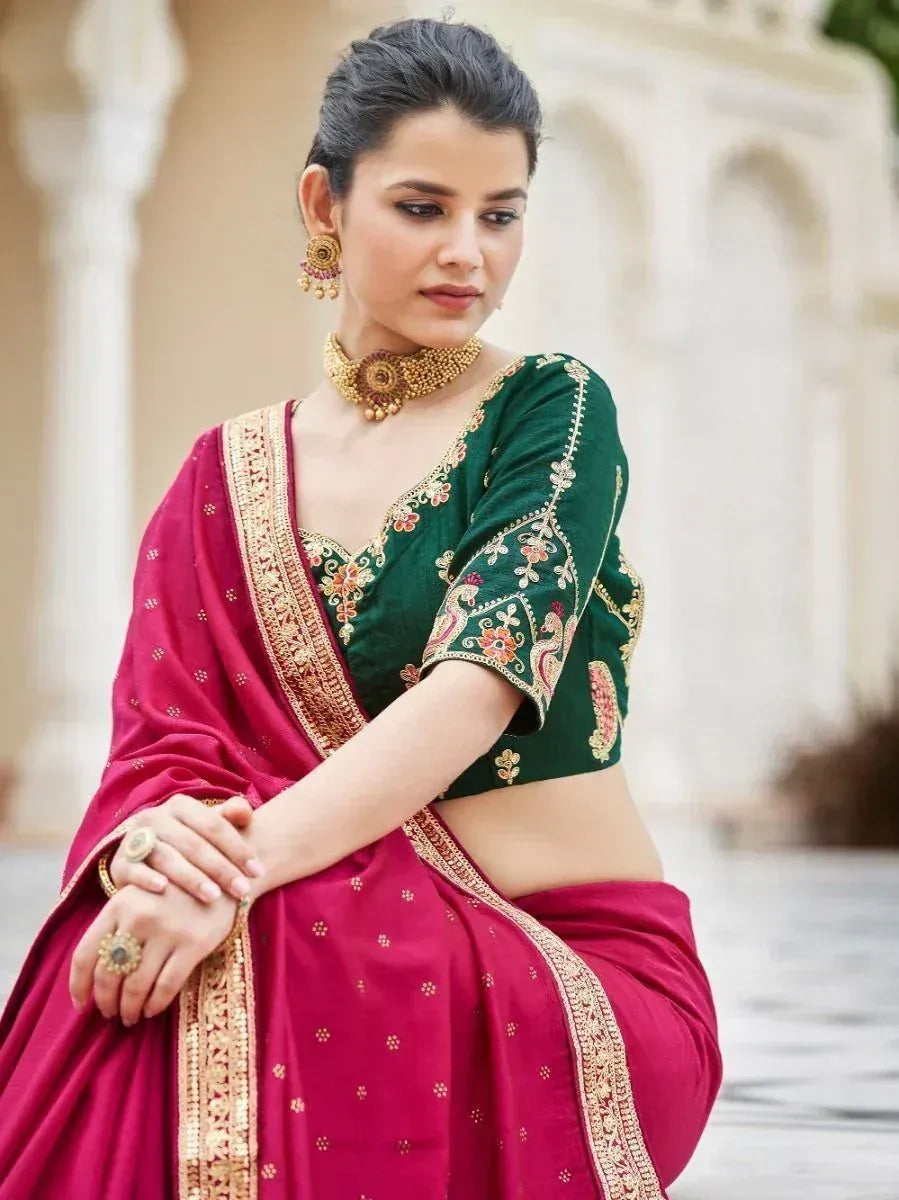 Woman in maroon saree with green embroidered blouse, gold jewelry, traditional Indian ethnic wear
