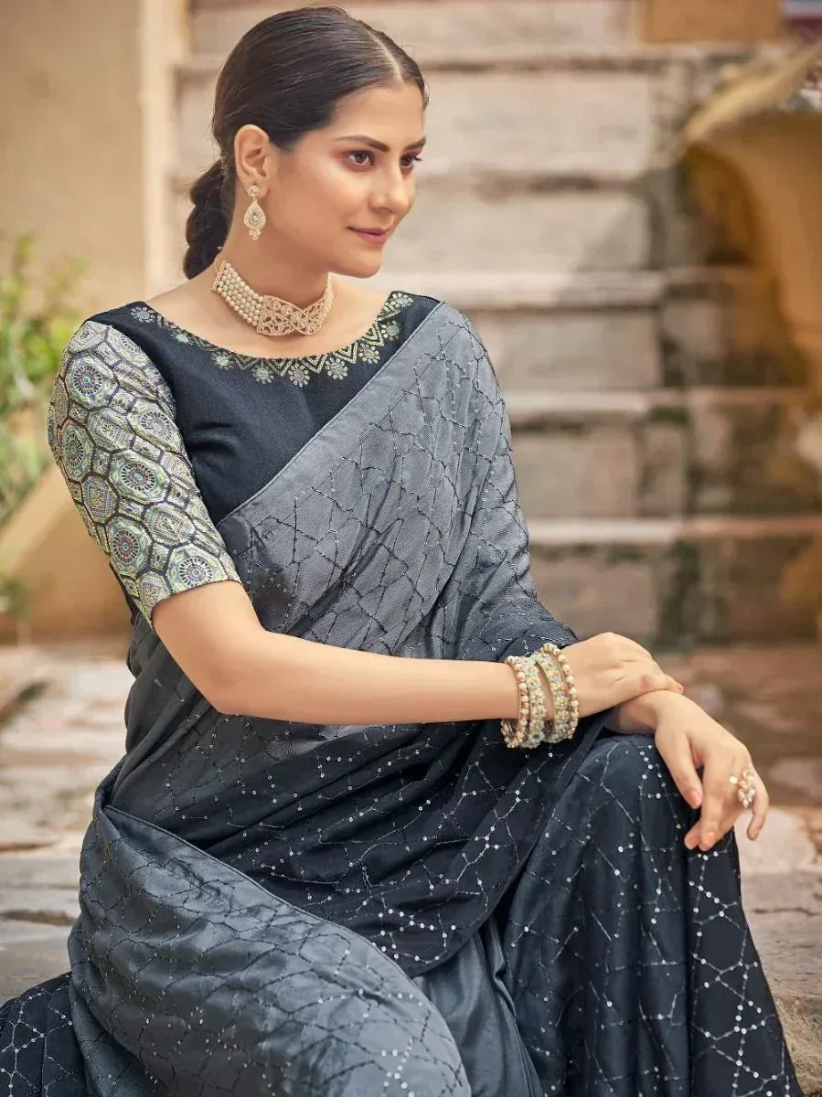 Elegant dark grey saree with geometric embroidery and embellished blouse, styled with pearl jewelry for Indian ethnic wear.