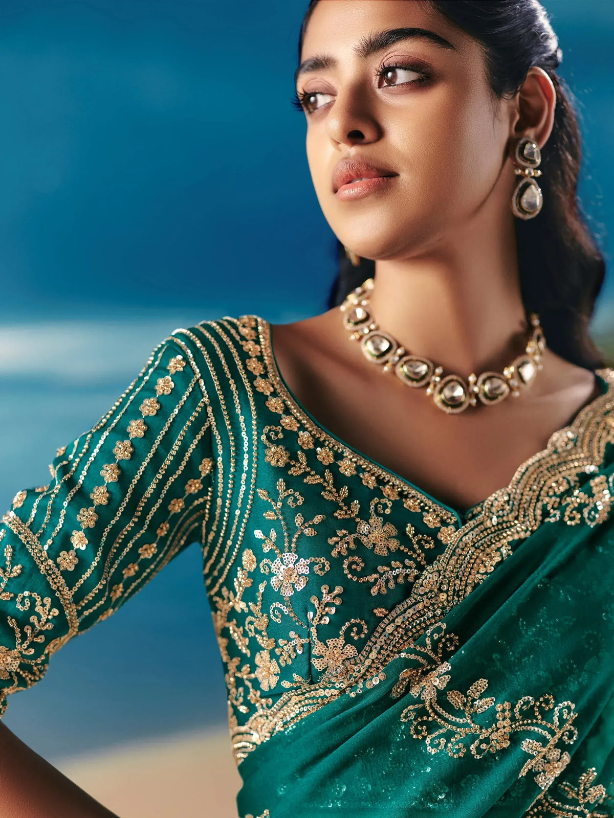 Emerald green designer saree with gold floral embroidery and sequins, perfect for Indian ethnic wear occasions.