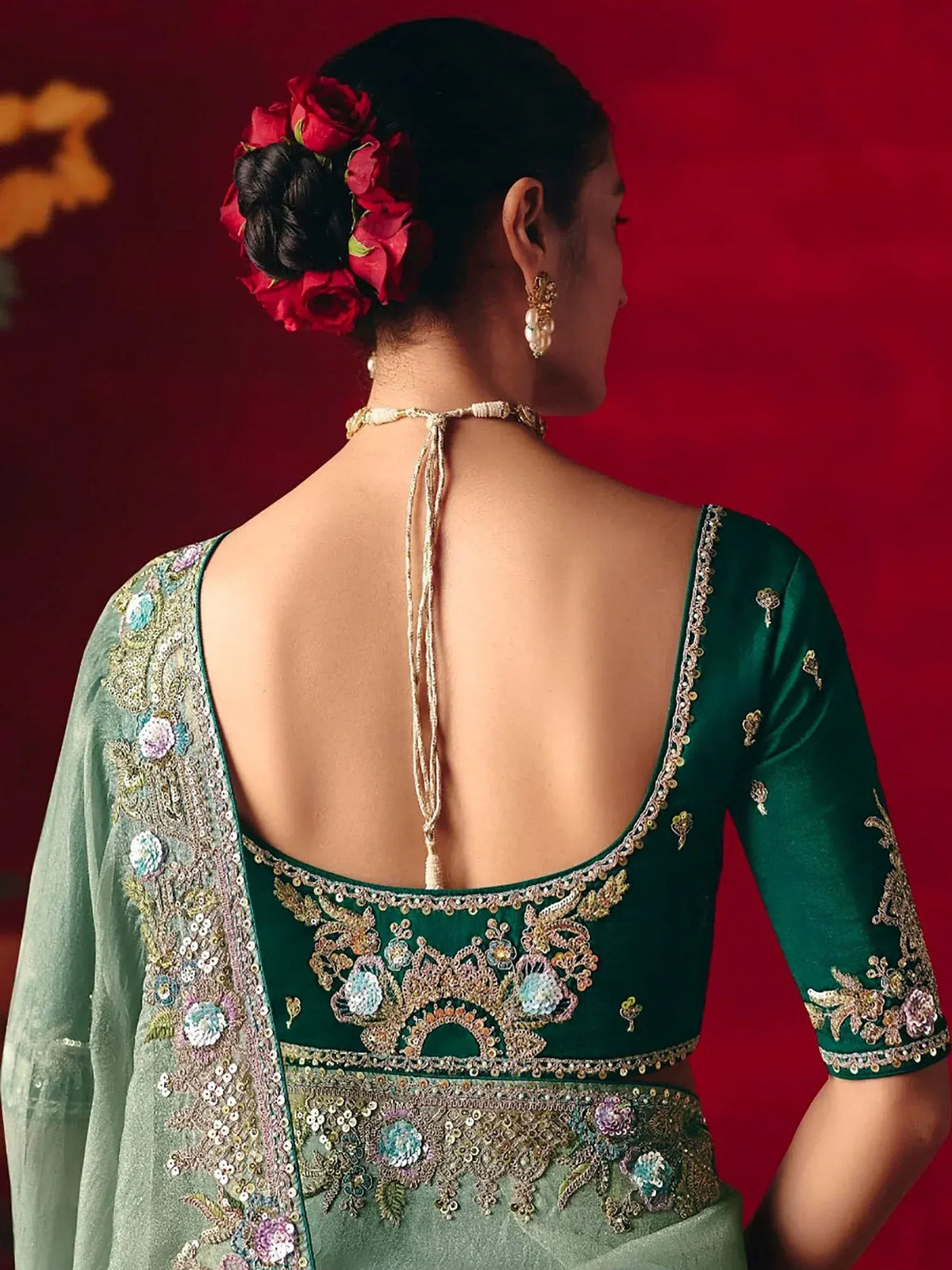 Emerald green embroidered lehenga choli with floral back design and red rose hair accessory