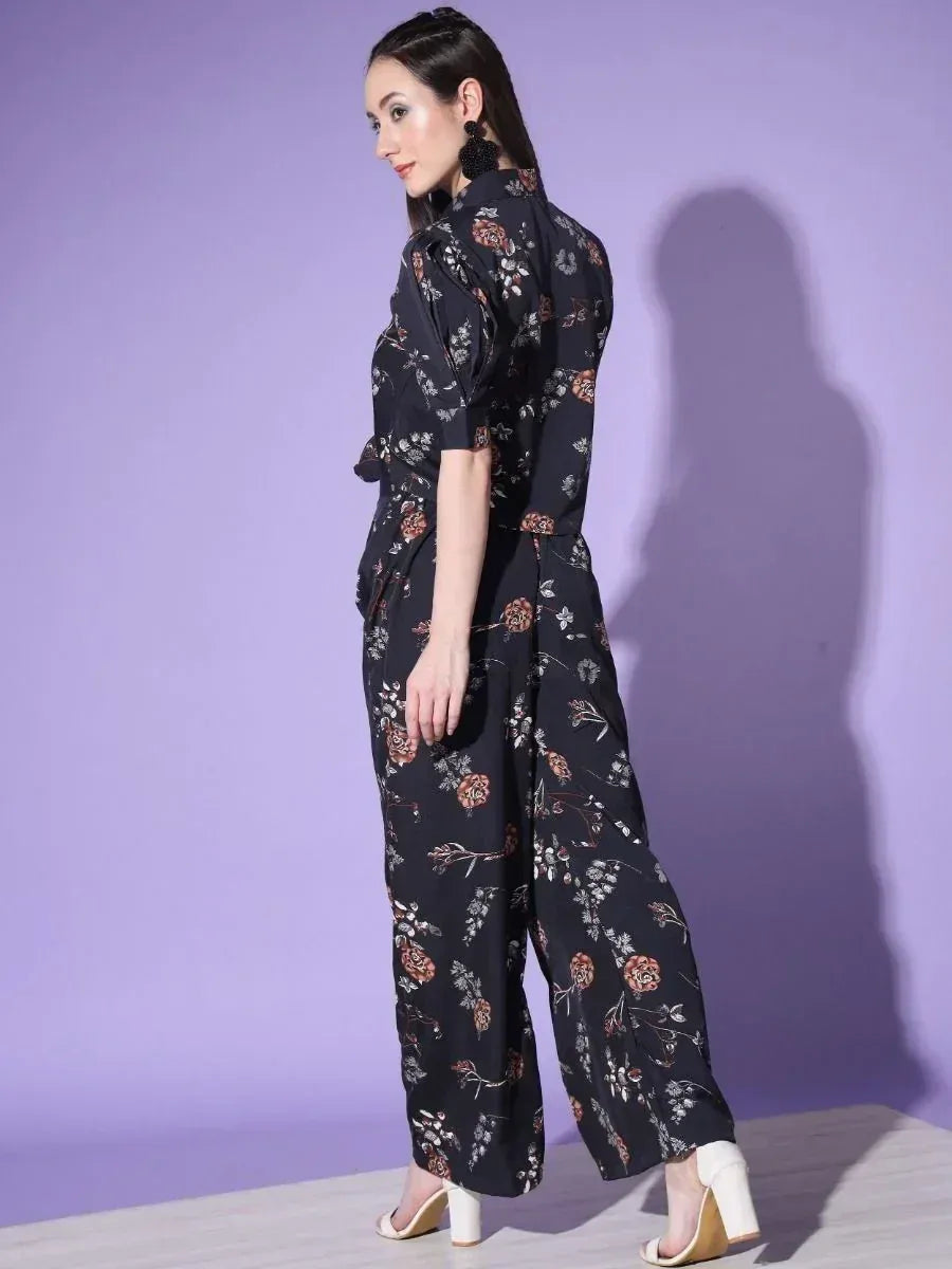 Black floral print ethnic jumpsuit with wide legs and short sleeves, styled with white heels