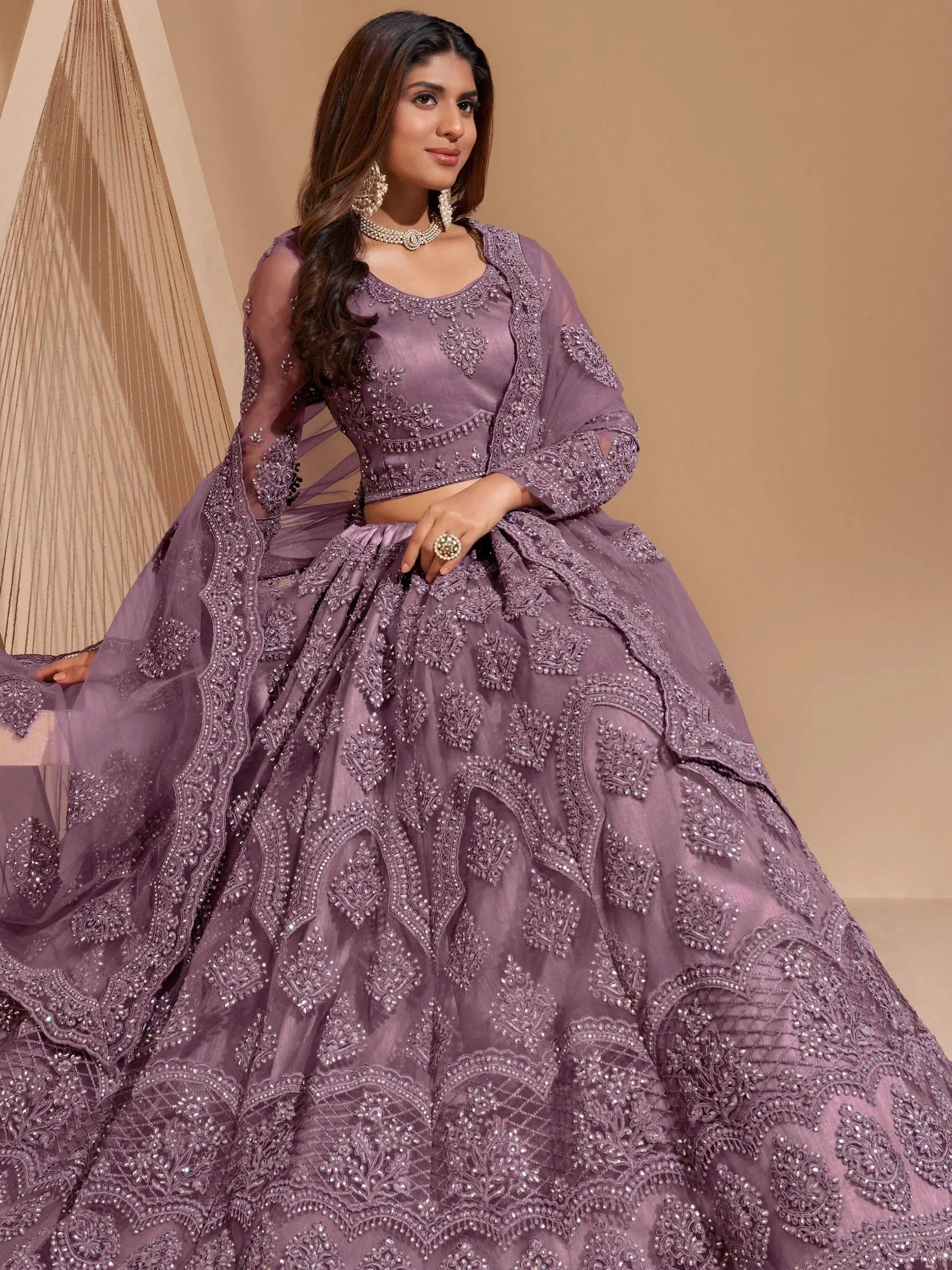 Elegant purple designer lehenga choli with heavy embroidery and sheer sleeves, perfect for Indian weddings.