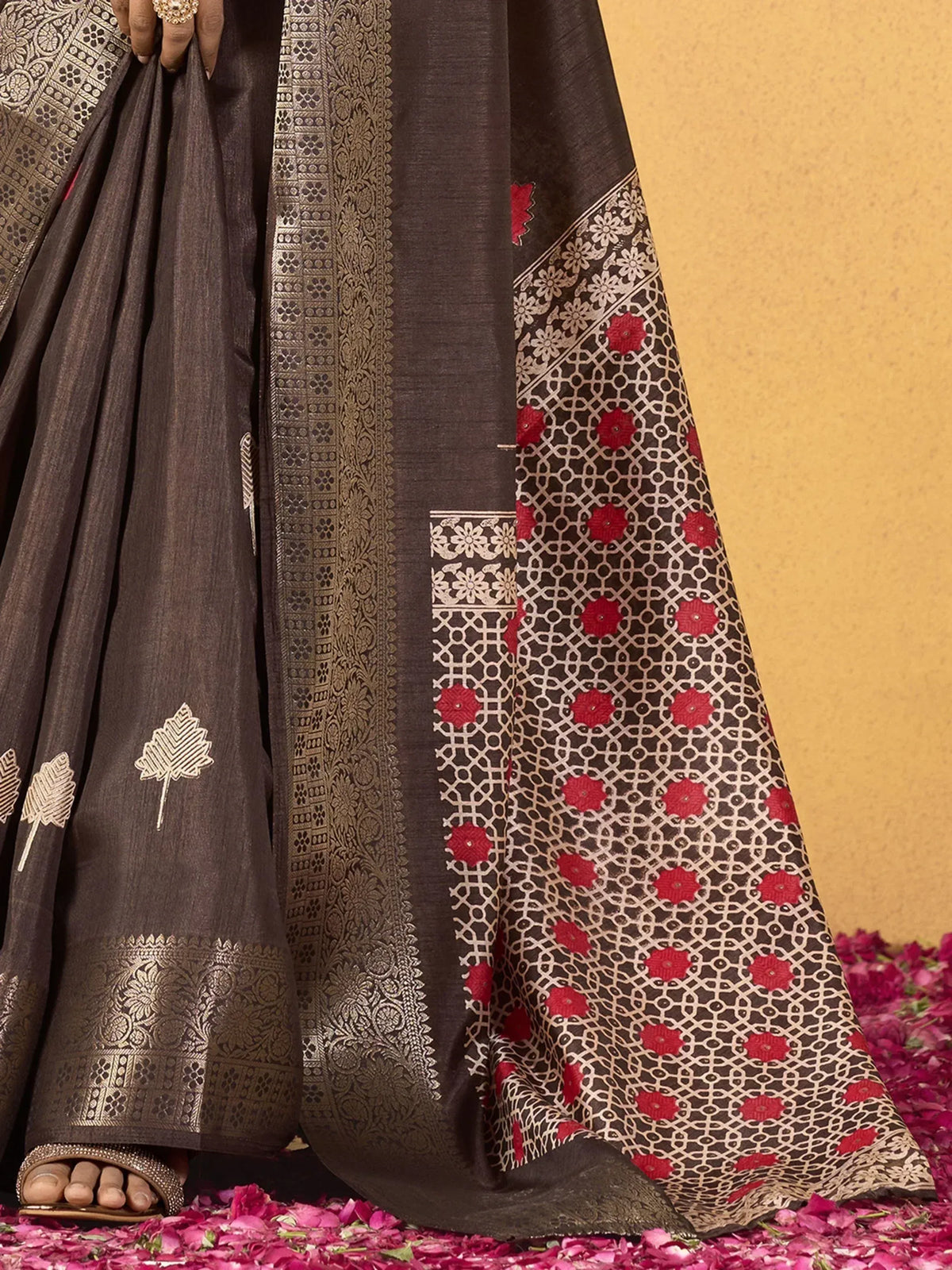Brown ethnic saree with gold and red floral embroidery, intricate border, and leaf motifs on silk fabric
