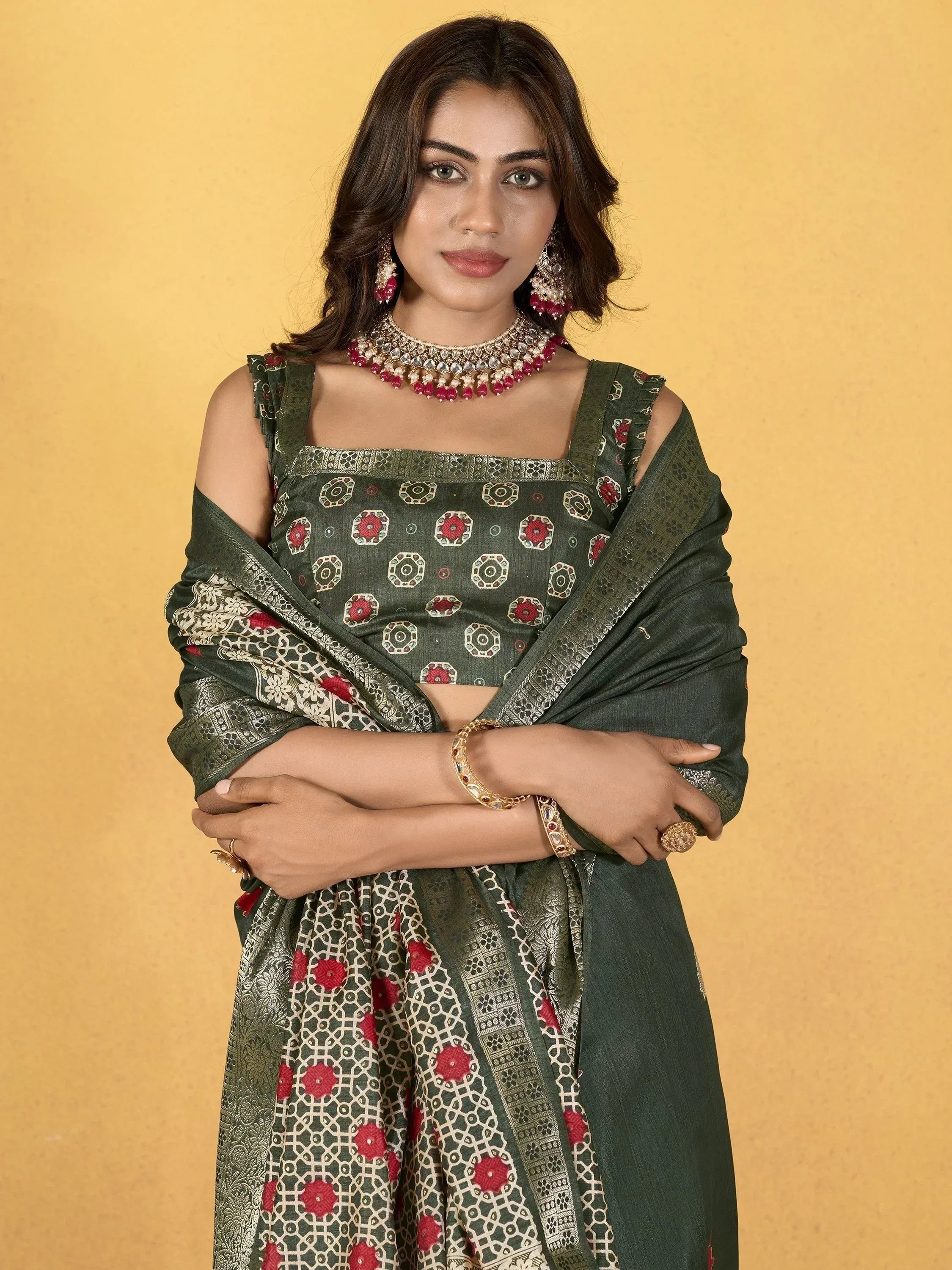 Woman in olive green printed ethnic saree with red floral motifs and gold jewelry, styled for festive occasions.