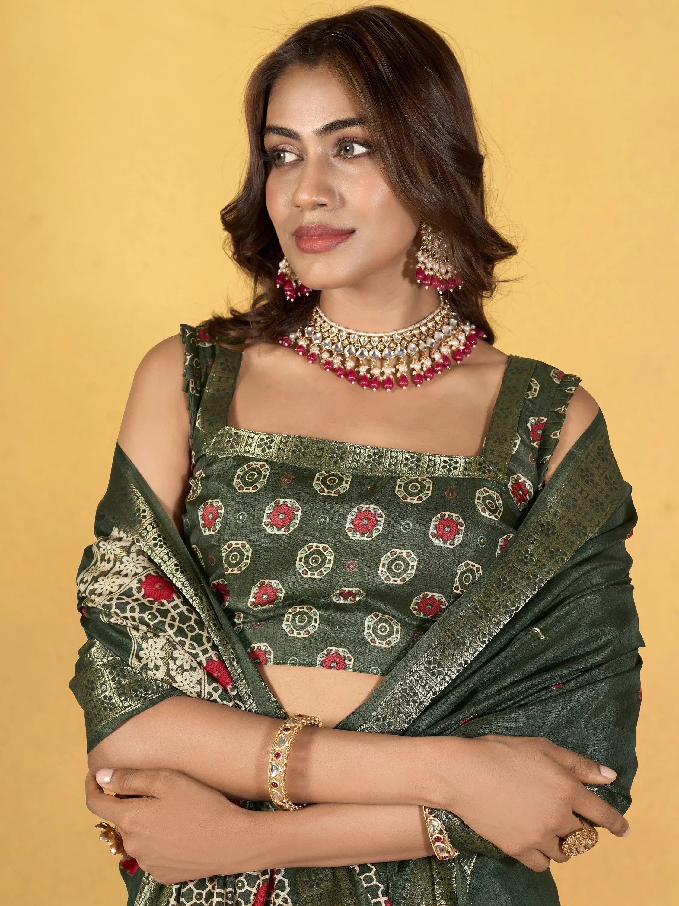 Woman in green printed saree with gold embroidery, paired with traditional jewelry for ethnic wear