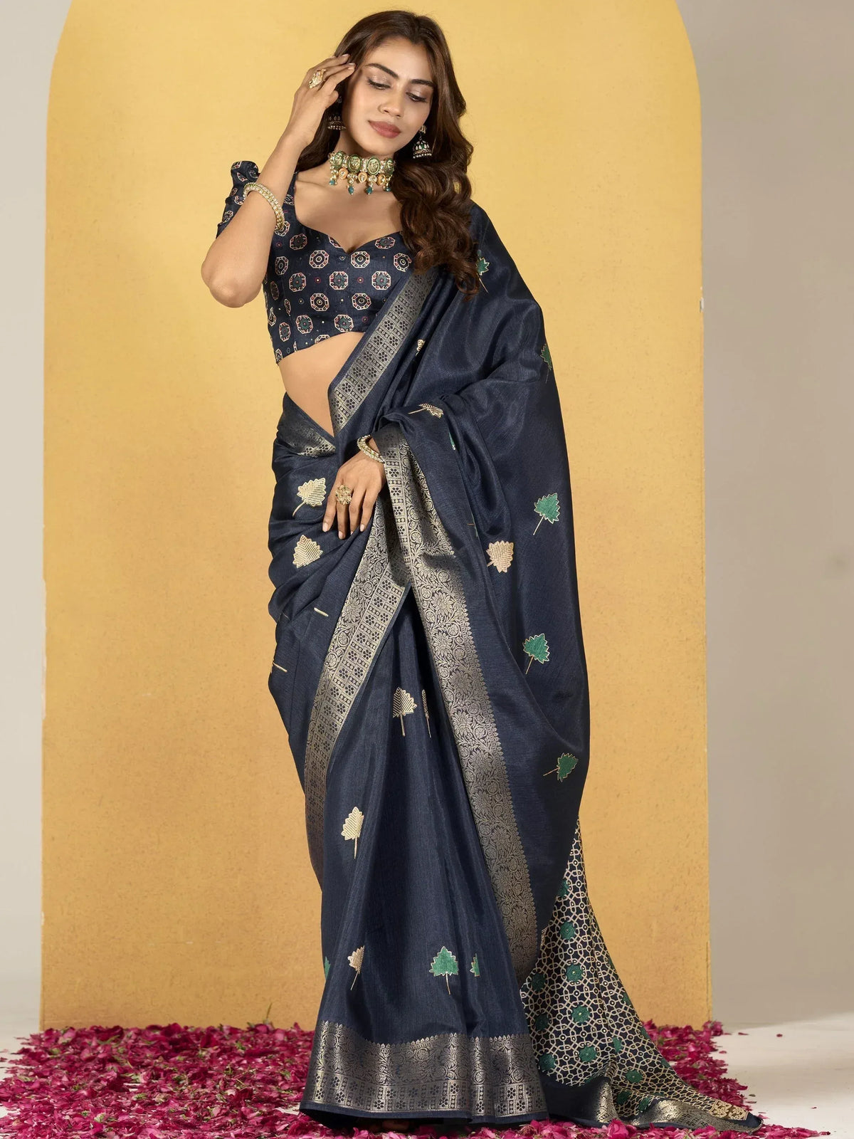 Navy blue designer saree with gold and green leaf embroidery, paired with matching blouse and traditional jewelry
