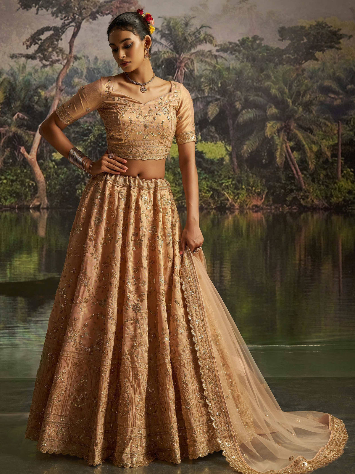 Elegant gold embroidered lehenga choli with floral hair accessories, perfect for Indian weddings and festive occasions.