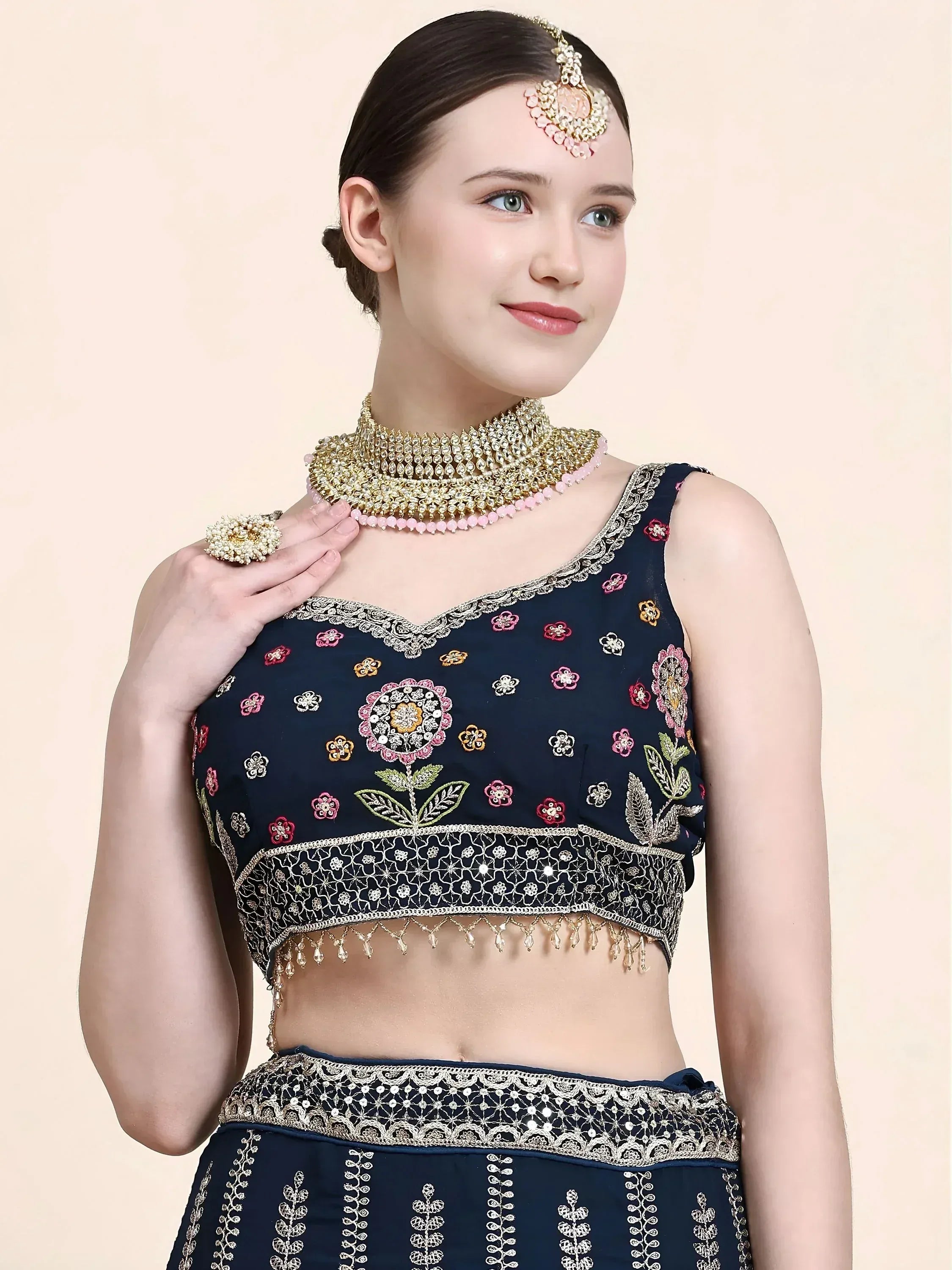 Navy blue embroidered lehenga choli with floral motifs, gold detailing, and traditional Indian jewelry