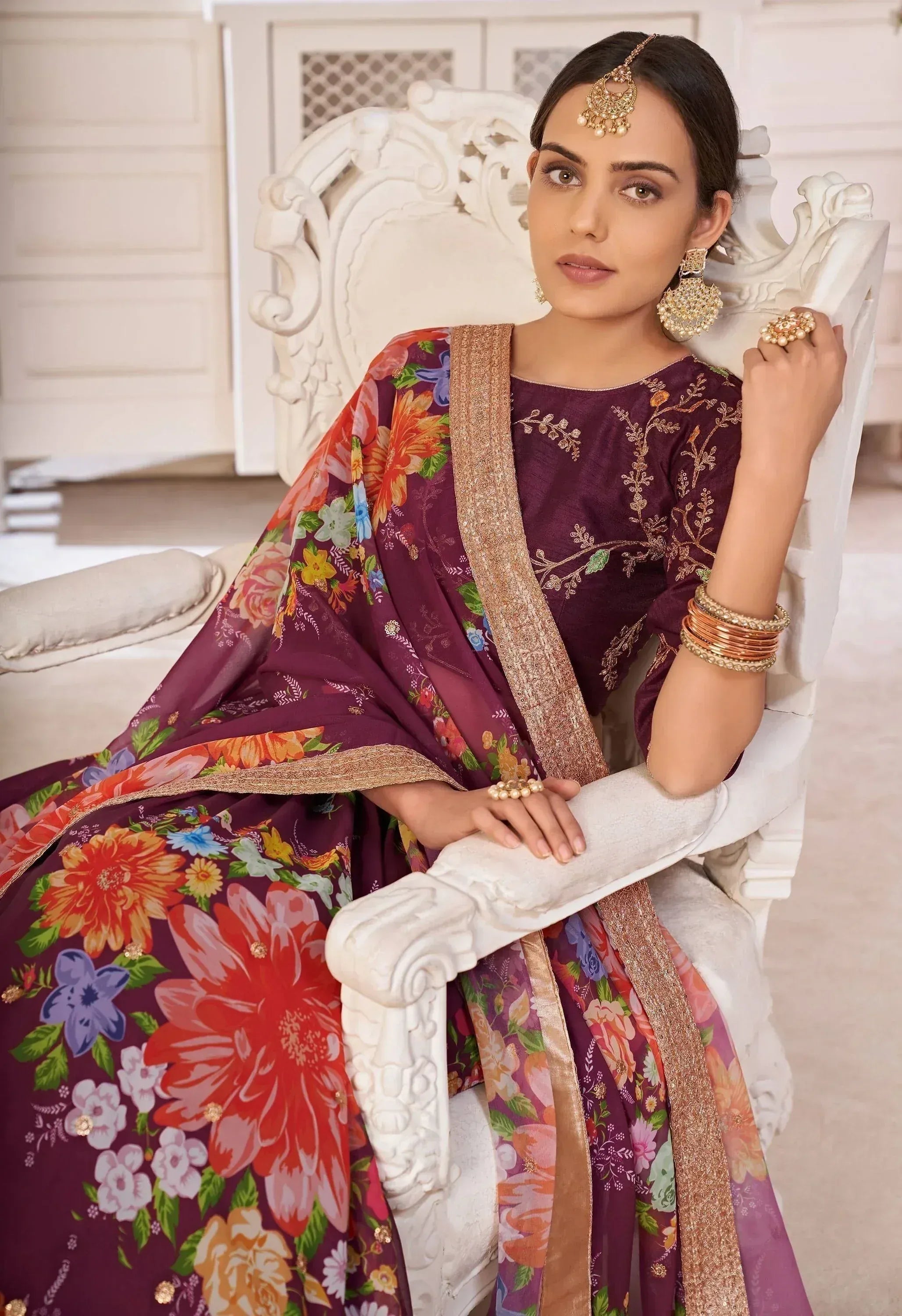 Woman in maroon floral ethnic salwar kameez with gold embroidery, styled with traditional jewelry