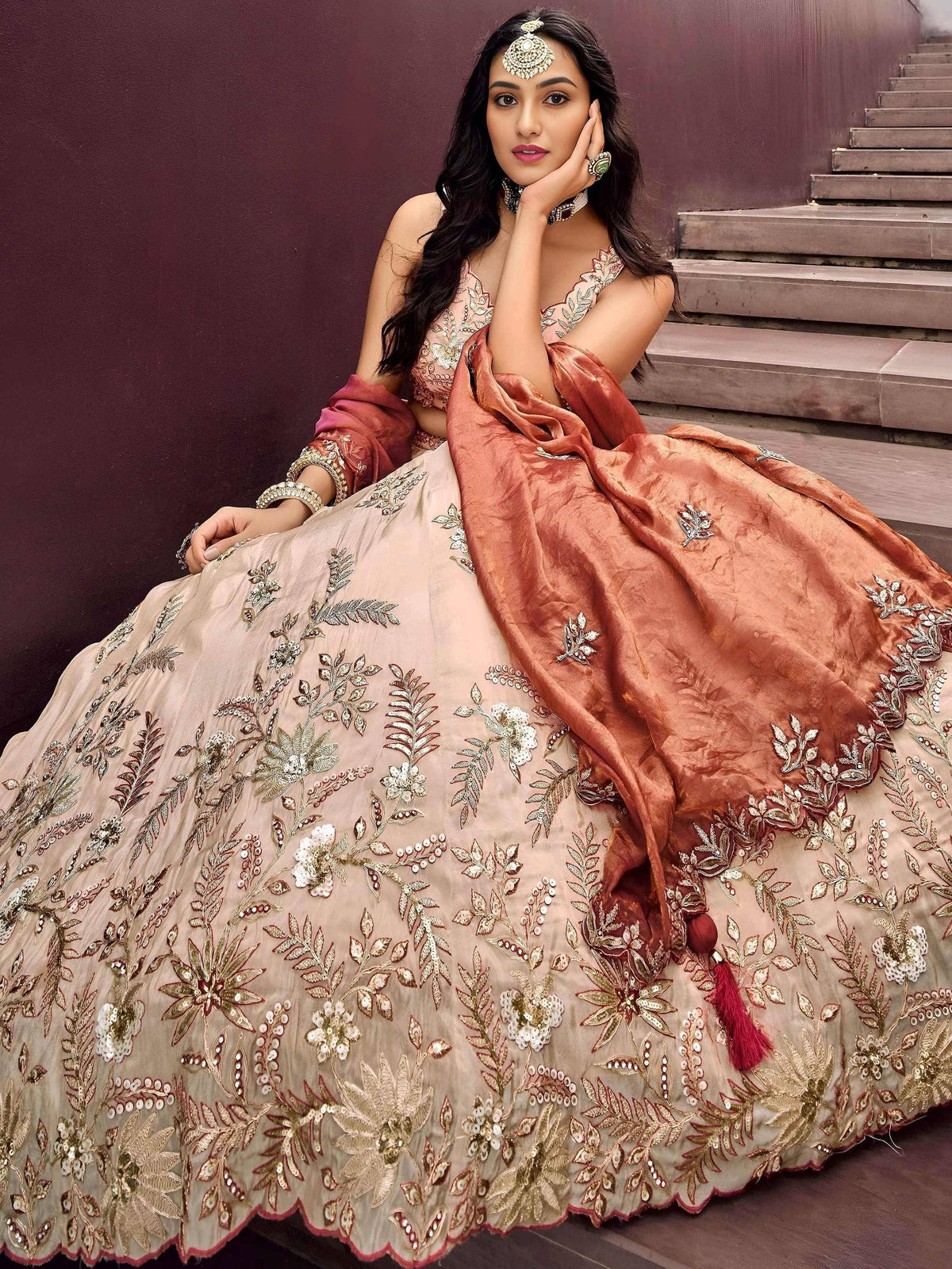 Elegant beige lehenga choli with floral embroidery and rust dupatta, perfect for Indian weddings and festive occasions.