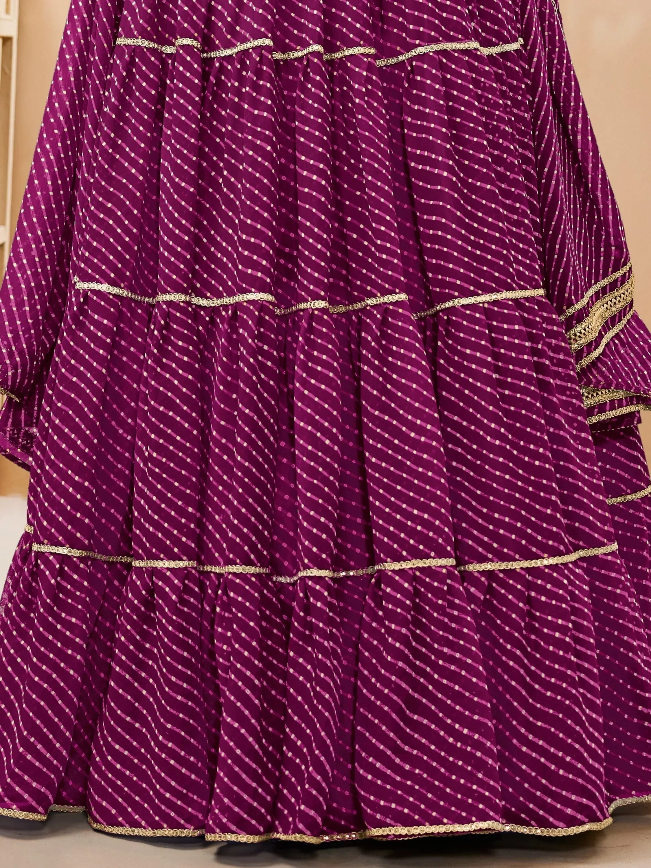 Purple tiered ethnic gown with gold trim and diagonal dot pattern, ideal for festive occasions