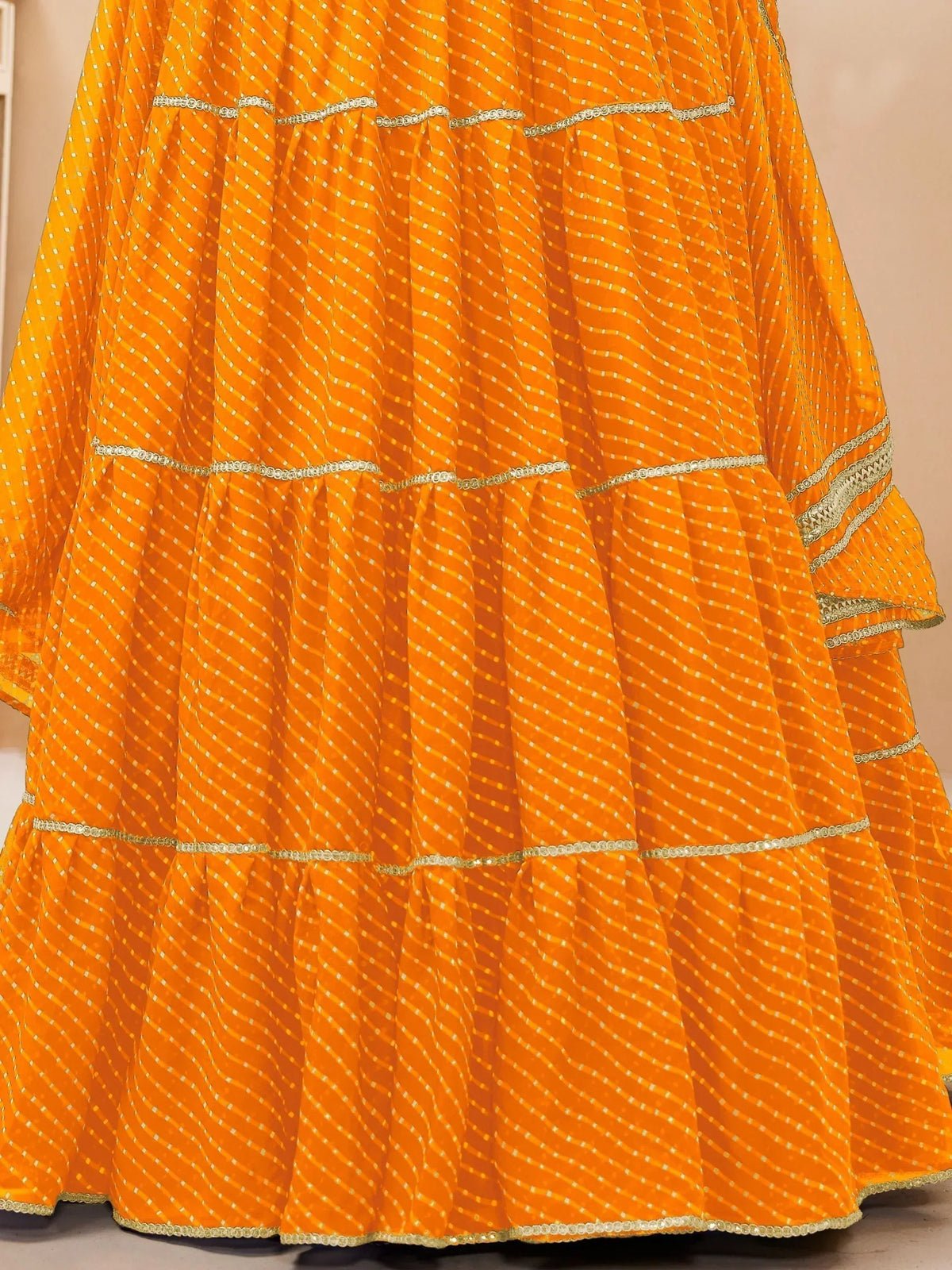 Vibrant orange tiered lehenga with gold embroidery and sequin detailing, perfect for Indian ethnic wear.