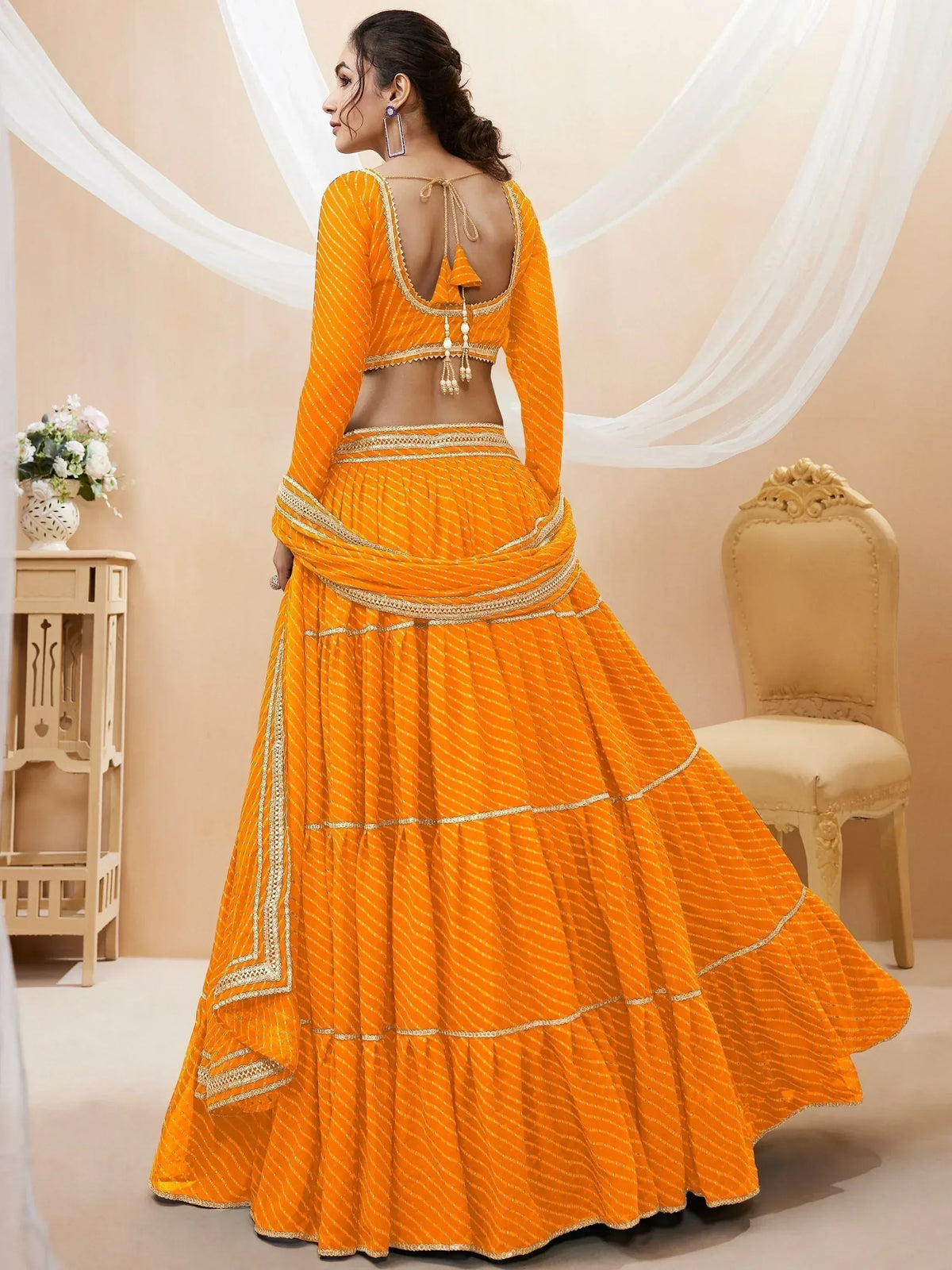 Vibrant orange designer lehenga choli with gold embroidery, backless blouse, and pleated skirt for Indian ethnic wear
