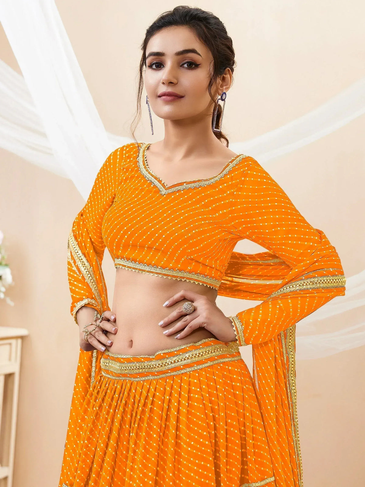 Vibrant orange ethnic lehenga choli with gold embroidery and mirror work, perfect for festive occasions