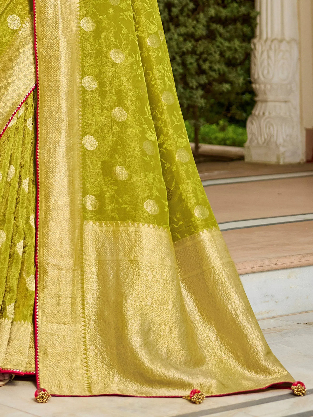 Lime green designer lehenga with gold floral embroidery and red border, perfect for Indian ethnic wear.