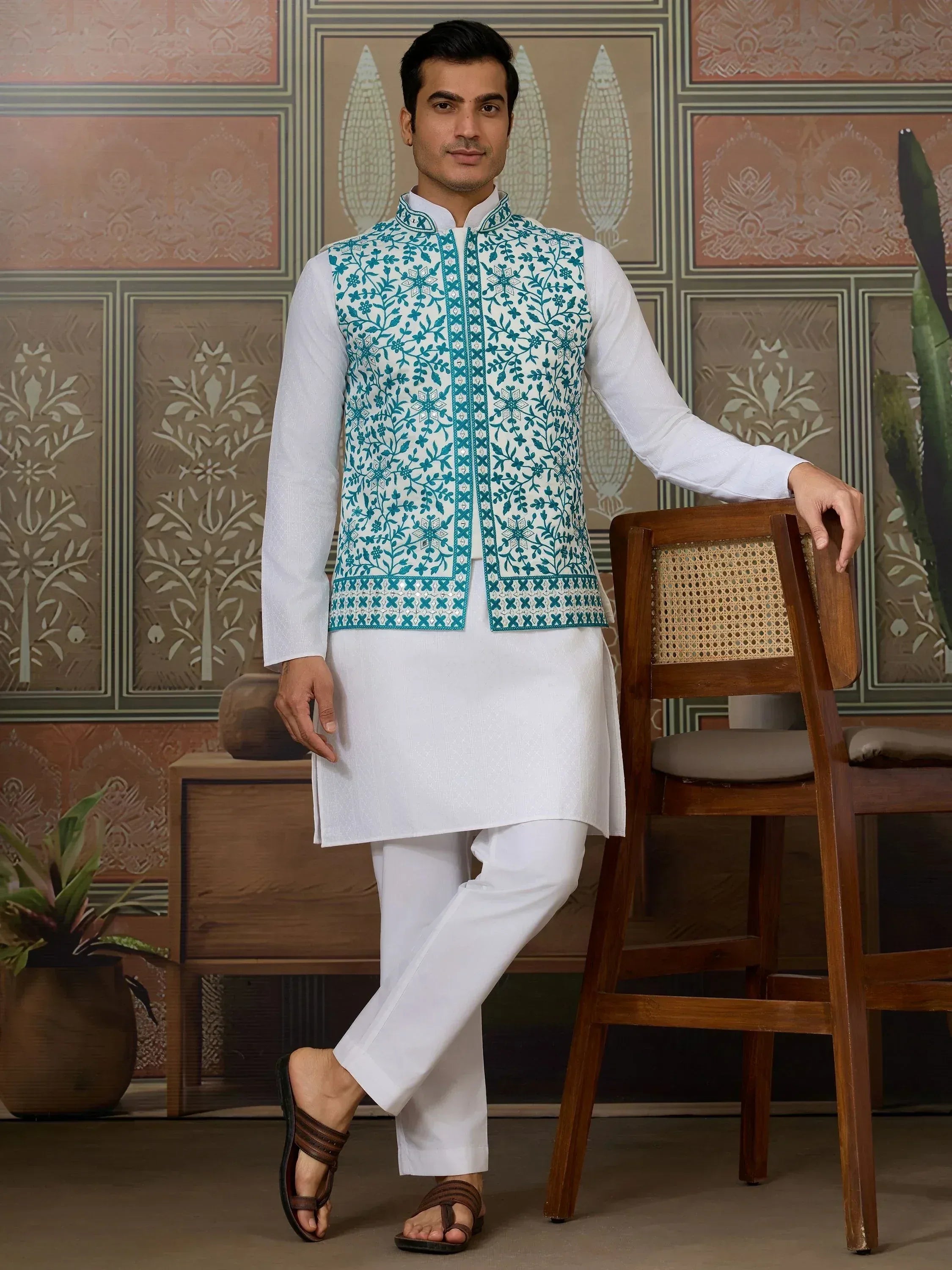 Man in white kurta pajama with teal embroidered vest, ethnic Indian wear
