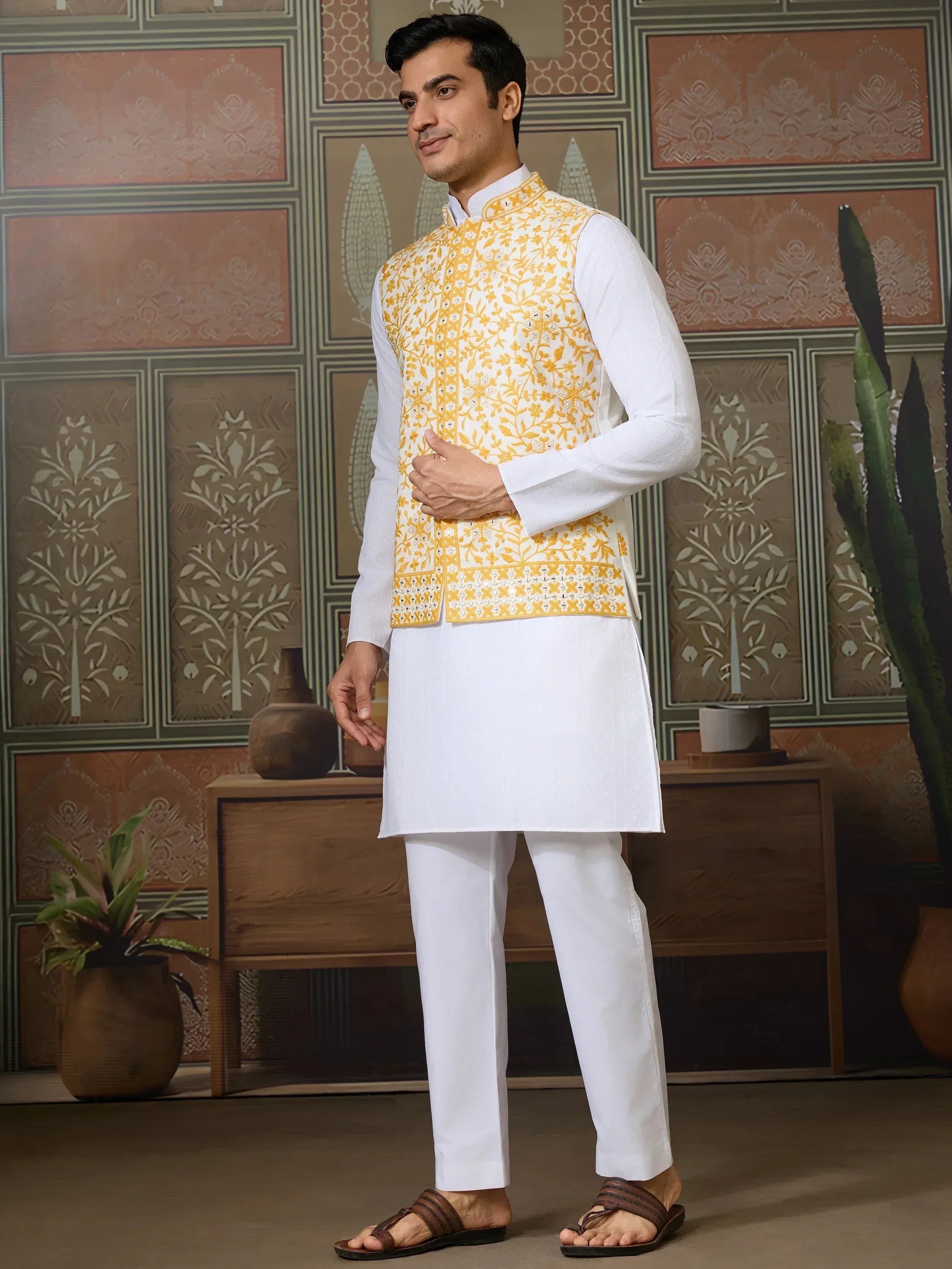 Man in white kurta pajama with yellow floral embroidered vest, Indian ethnic wear