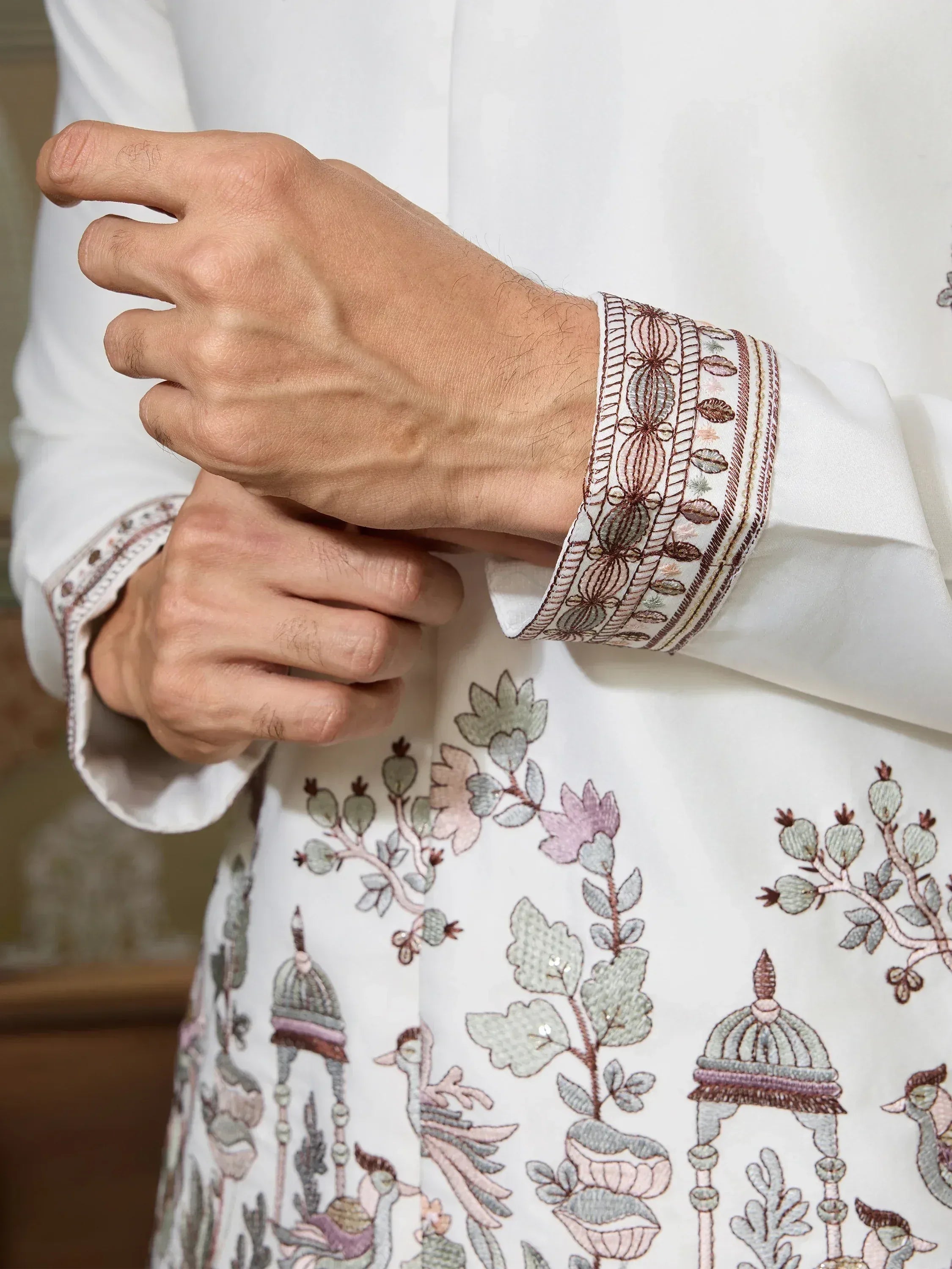 White kurta with intricate floral and bird embroidery, detailed cuff design for ethnic wear
