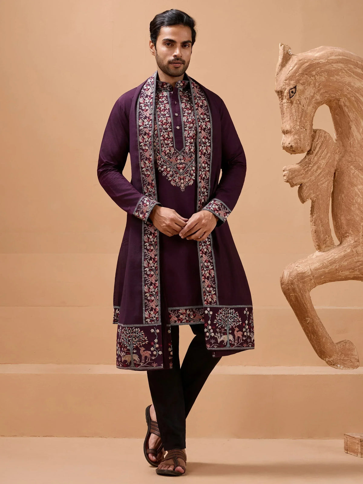 Man in purple embroidered kurta with floral and deer motifs, paired with black pants and sandals