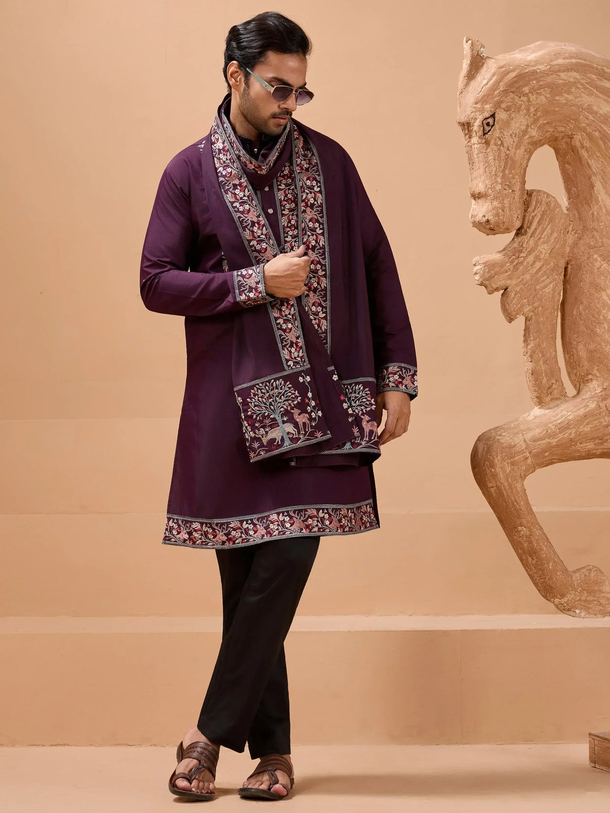 Man in purple embroidered kurta with matching stole, black pants, and sandals, styled for ethnic wear.