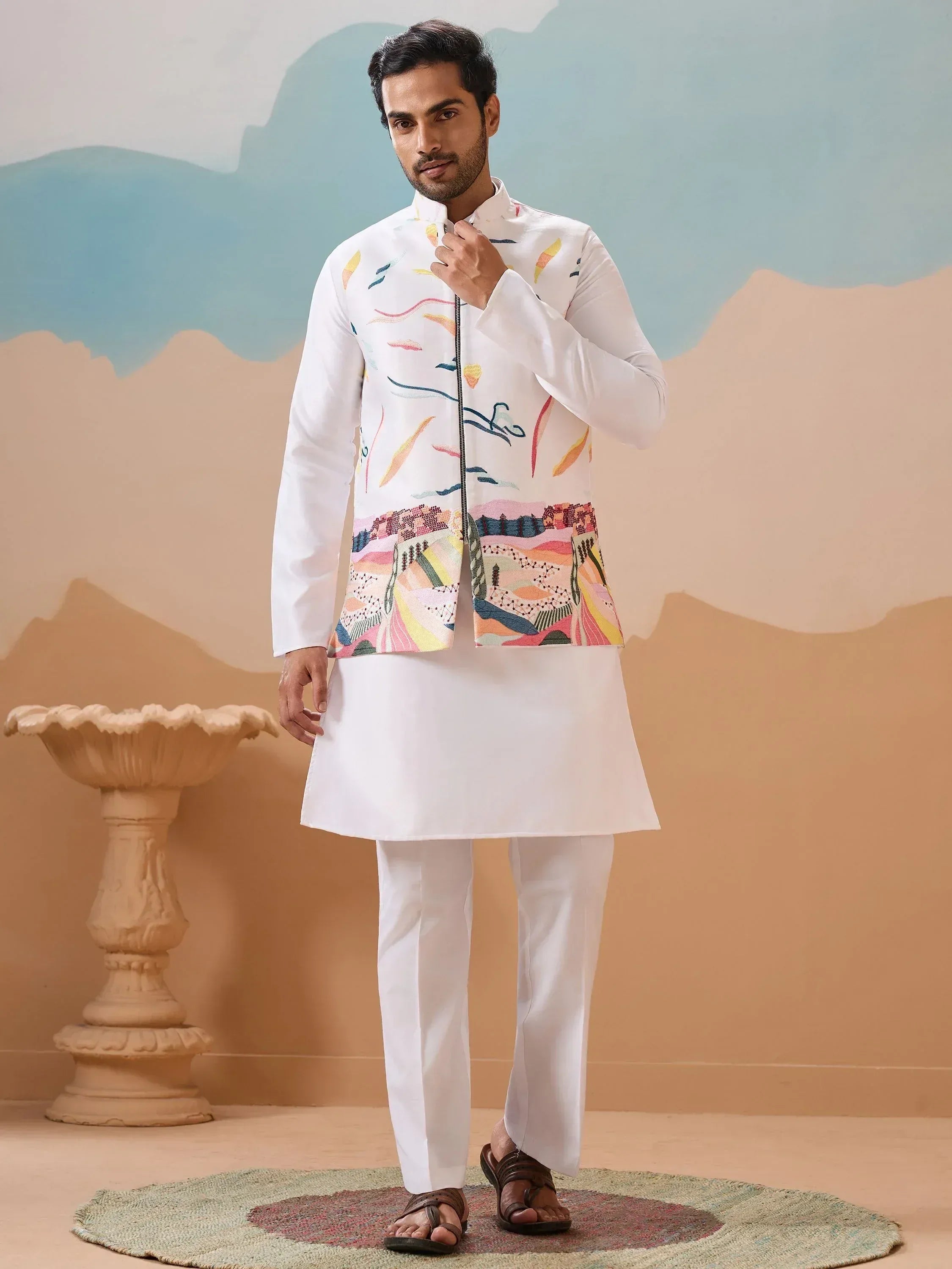 Man in white kurta set with colorful embroidered jacket, ethnic Indian wear for men
