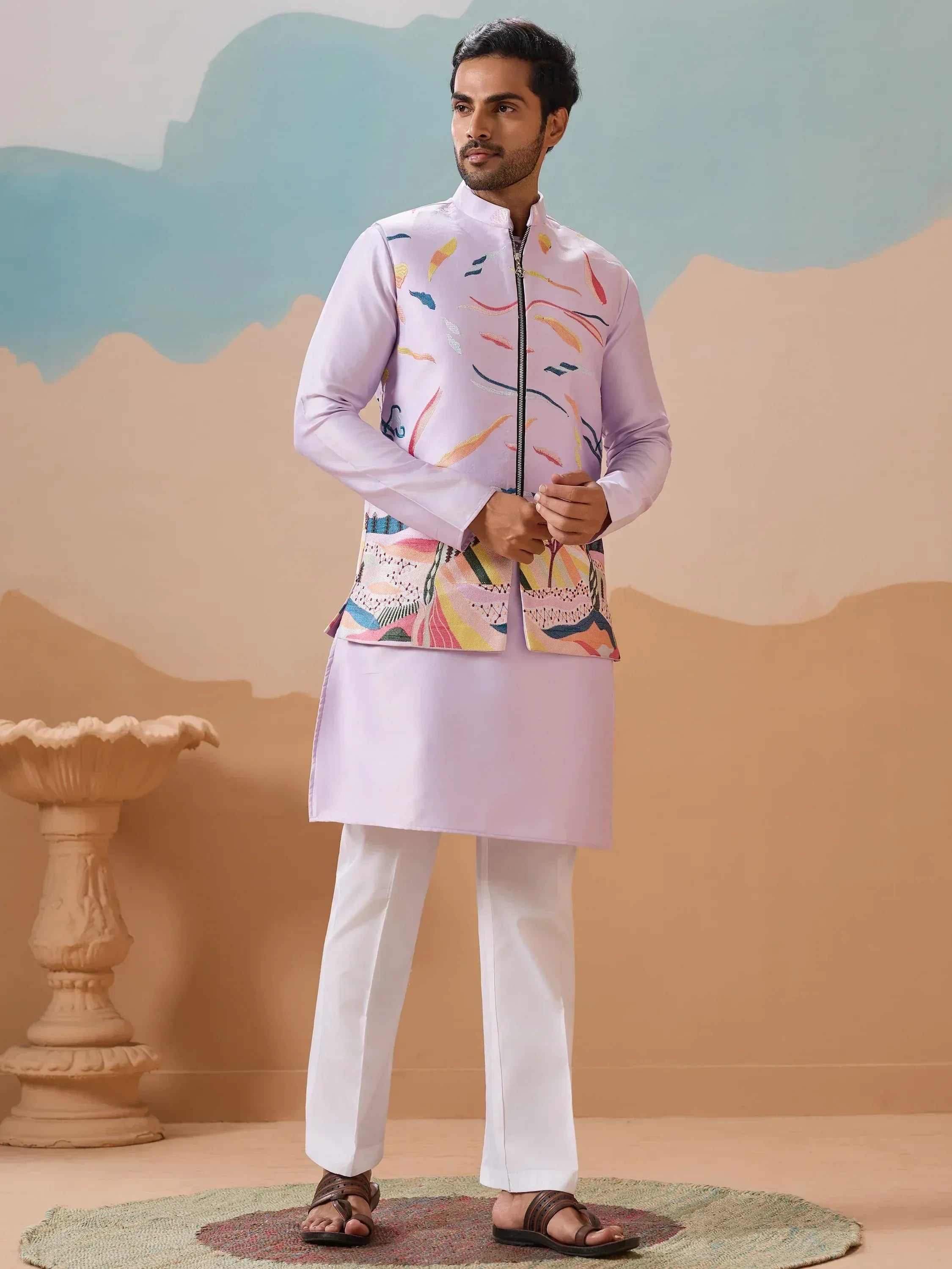 Man in lavender kurta with colorful printed jacket, white pants, ethnic Indian wear