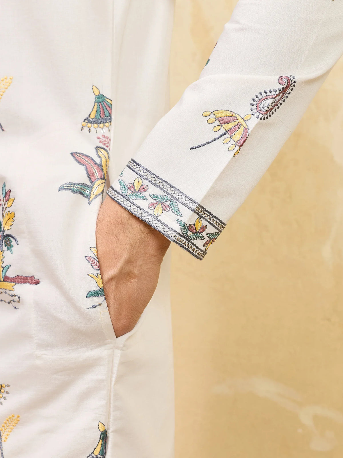 Close-up of a white men's ethnic kurta with colorful floral embroidery on the sleeve and body