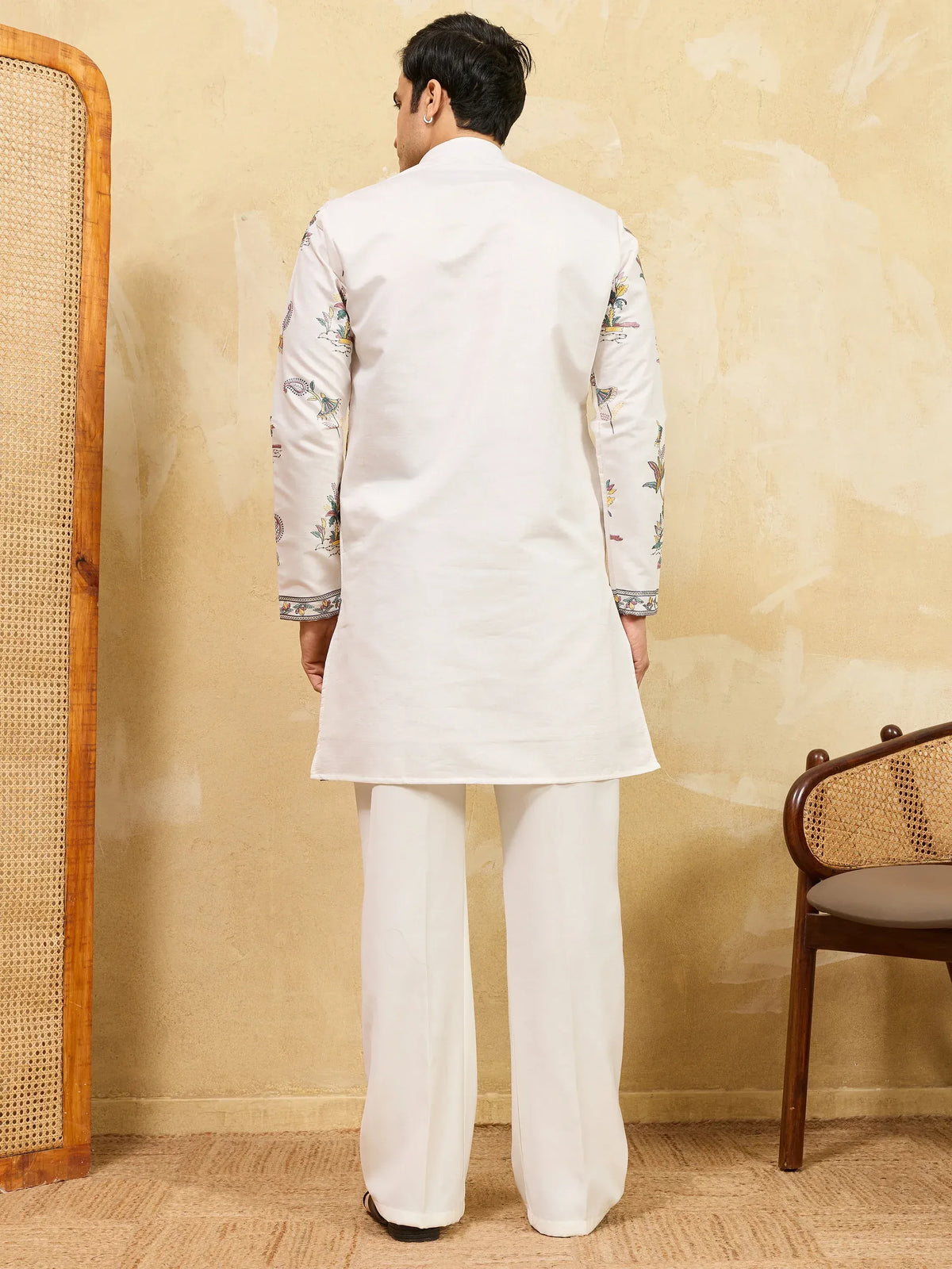 Back view of a man wearing a white floral embroidered ethnic kurta and matching trousers.
