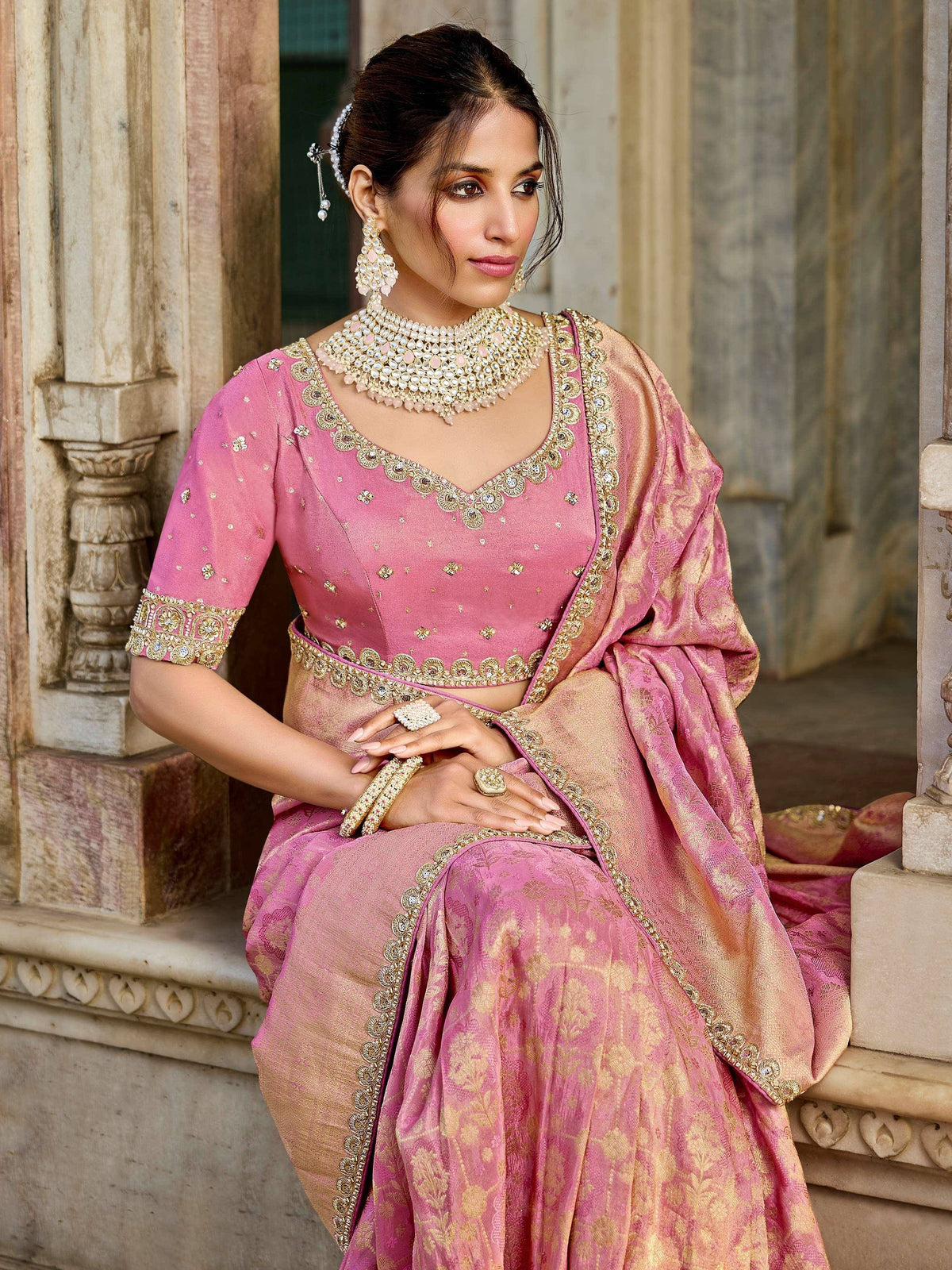Pink and gold embroidered lehenga choli with heavy jewelry, perfect for Indian weddings and festive occasions.