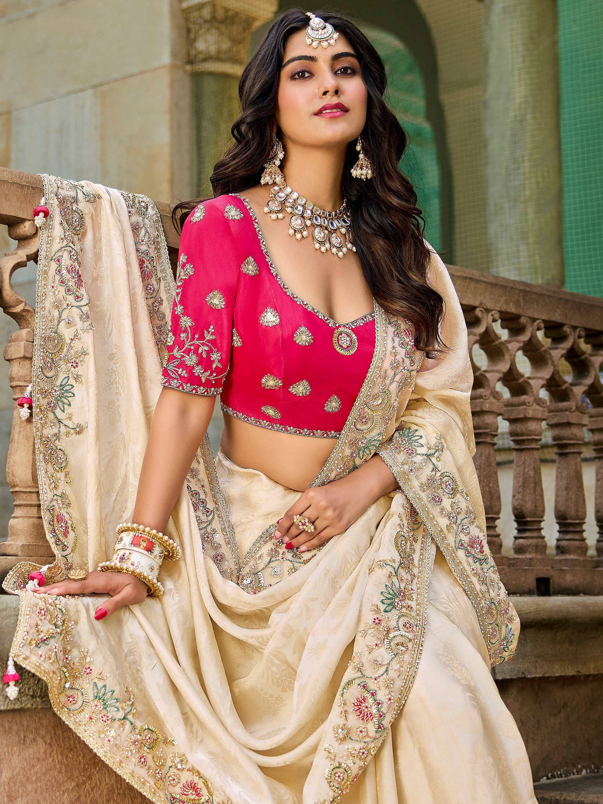 Woman in pink embroidered blouse and cream lehenga choli with floral detailing, perfect for Indian ethnic wear.