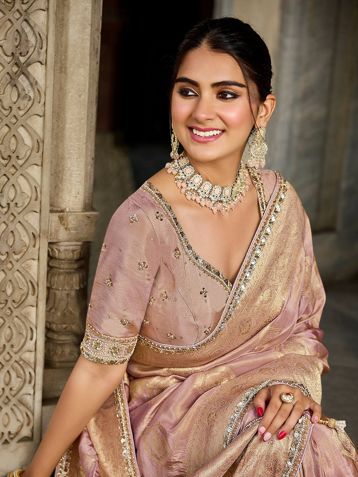 Elegant woman in pink and gold embroidered saree with matching jewelry, perfect for Indian ethnic occasions.