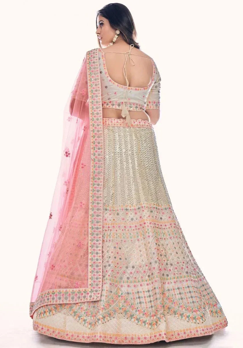 Elegant off-white lehenga choli with pink dupatta, floral embroidery, and open back blouse for Indian ethnic wear