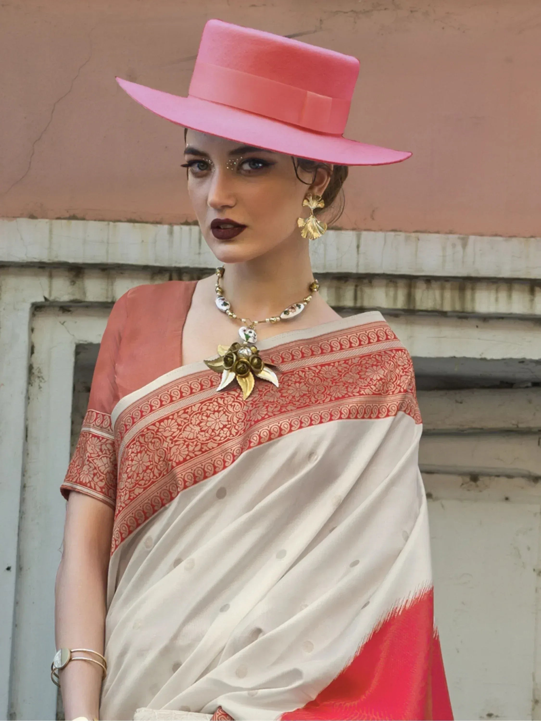 Woman in white and red ethnic saree with pink hat and gold jewelry, stylish Indian wear
