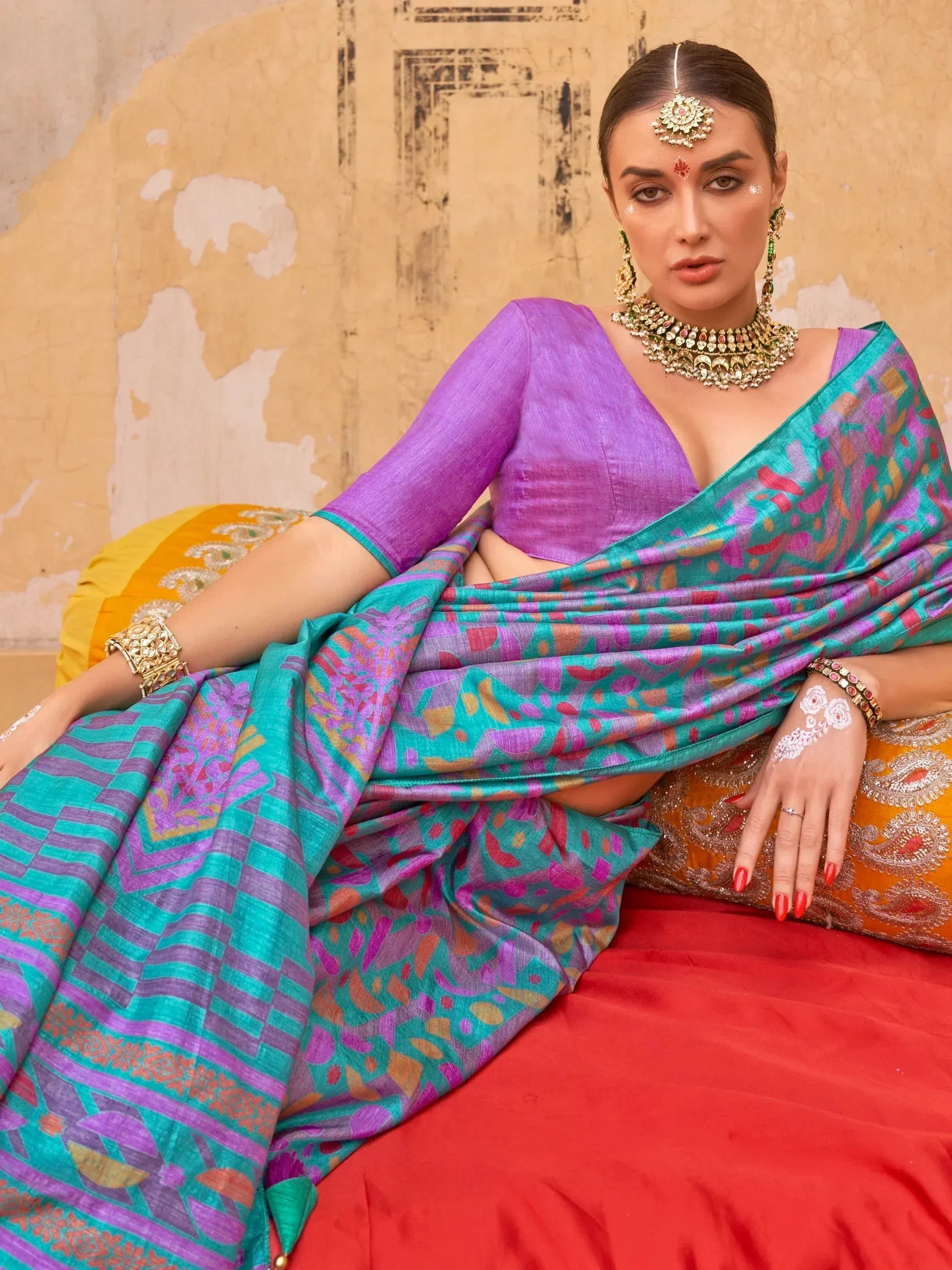 Woman in vibrant purple and teal printed saree with traditional jewelry, ethnic wear for festive occasions